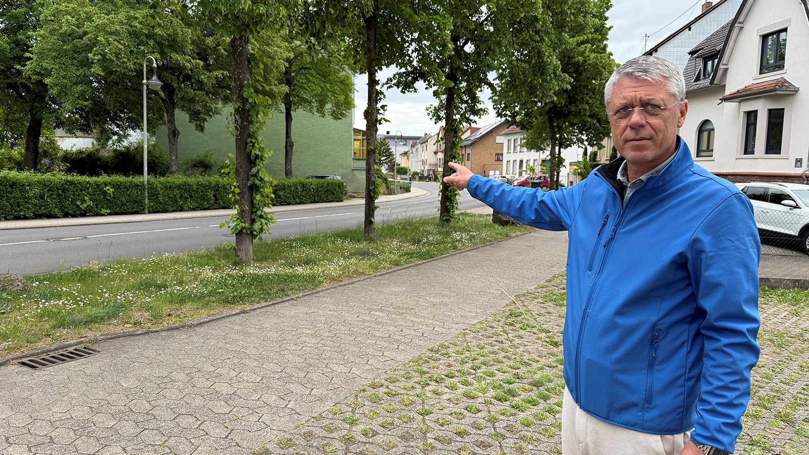 Rainer Lang (SPD), B&uuml;rgermeister von Kleinblittersdorf, deutet auf die vor einem Jahr &uuml;berflutete Ortsdurchfahrt. Heute ist von den Sch&auml;den nichts mehr zu sehen. Doch das Ereignis wirkt nach. Foto: Birgit Reichert/dpa +++ dpa-Bildfunk +++
