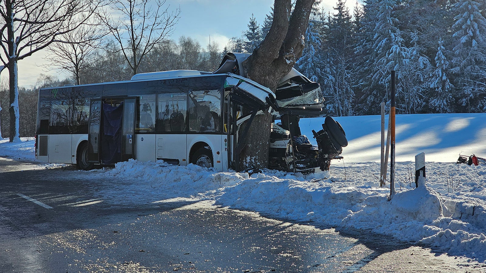 05.12.2023, Sachsen, Sehmatal-Cranzahl: Ein zerst&ouml;rter Schulbus steht nach der Kollision mit einem Streufahrzeug am Stra&szlig;enrand. Bei dem Unfall im Erzgebirge ist ein Kind get&ouml;tet worden. Mindestens zehn weitere Schulkinder wurden verletzt. Zudem wurden zwei Erwachsene - darunter der Busfahrer - schwer verletzt. (Zu dpa: &laquo;Kind bei Schulbusunfall im Erzgebirge get&ouml;tet - viele Verletzte&raquo;) Foto: Mike M&uuml;ller/TNN/dpa +++ dpa-Bildfunk +++