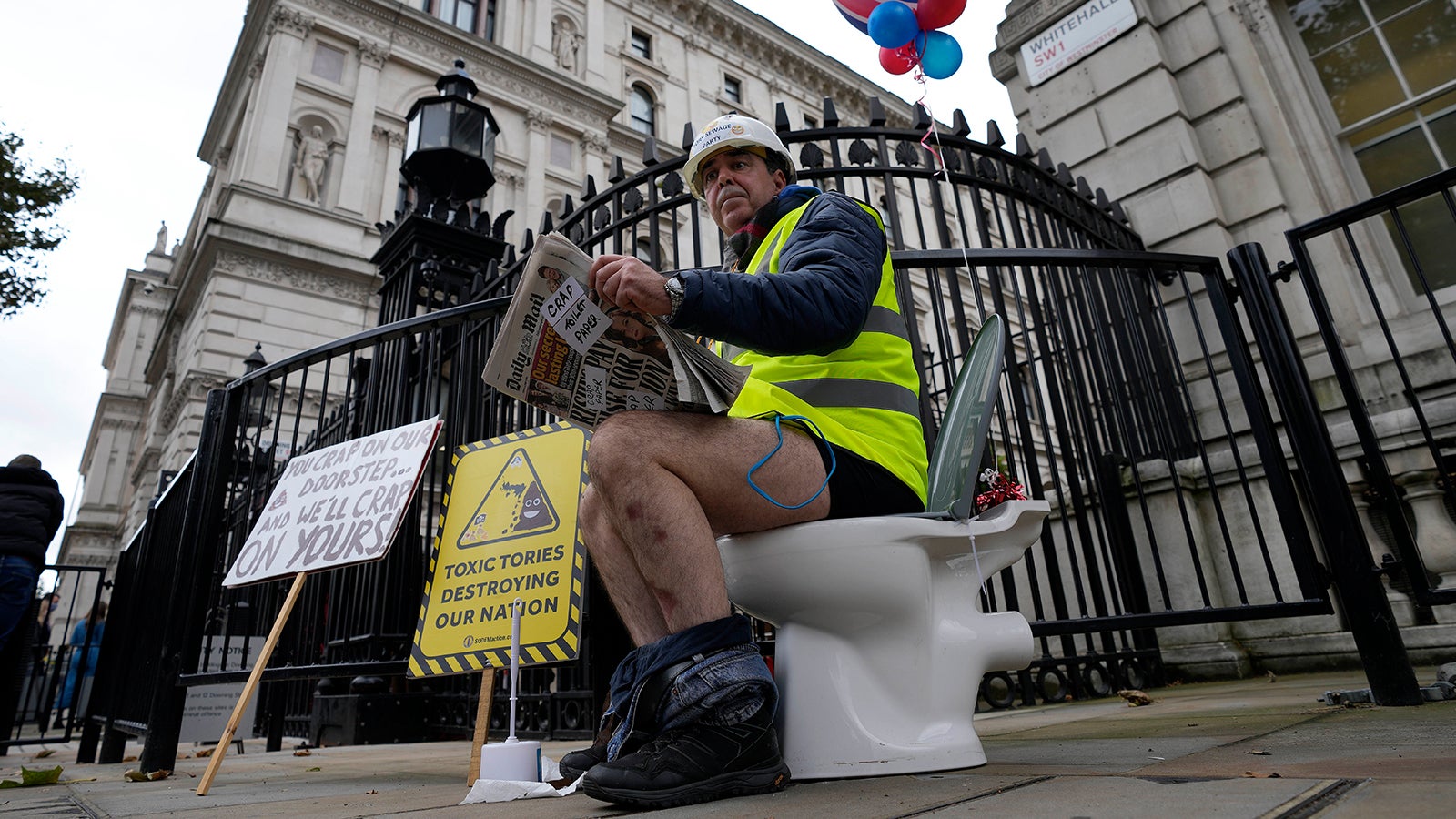ARCHIV - 26.10.2021, Gro&szlig;britannien, London: Steve Bray, einer der bekanntesten Brexit-Gegnern aus Gro&szlig;britannien, sitzt auf einer Toilette, die vor dem Cabinets Office steht, und liest Zeitung bei einem Protest gegen die Ableitung von nicht vollst&auml;ndig gereinigtem Wasser in Fl&uuml;sse und ins Meer. Ungekl&auml;rte Abw&auml;sser landen in britischen Seen und Fl&uuml;ssen sowie im Meer. (zu dpa &laquo;Shitstorm an britischen K&uuml;sten: Abw&auml;sser verleiden Urlaubsfreude&raquo;) Foto: Frank Augstein/AP/dpa +++ dpa-Bildfunk +++