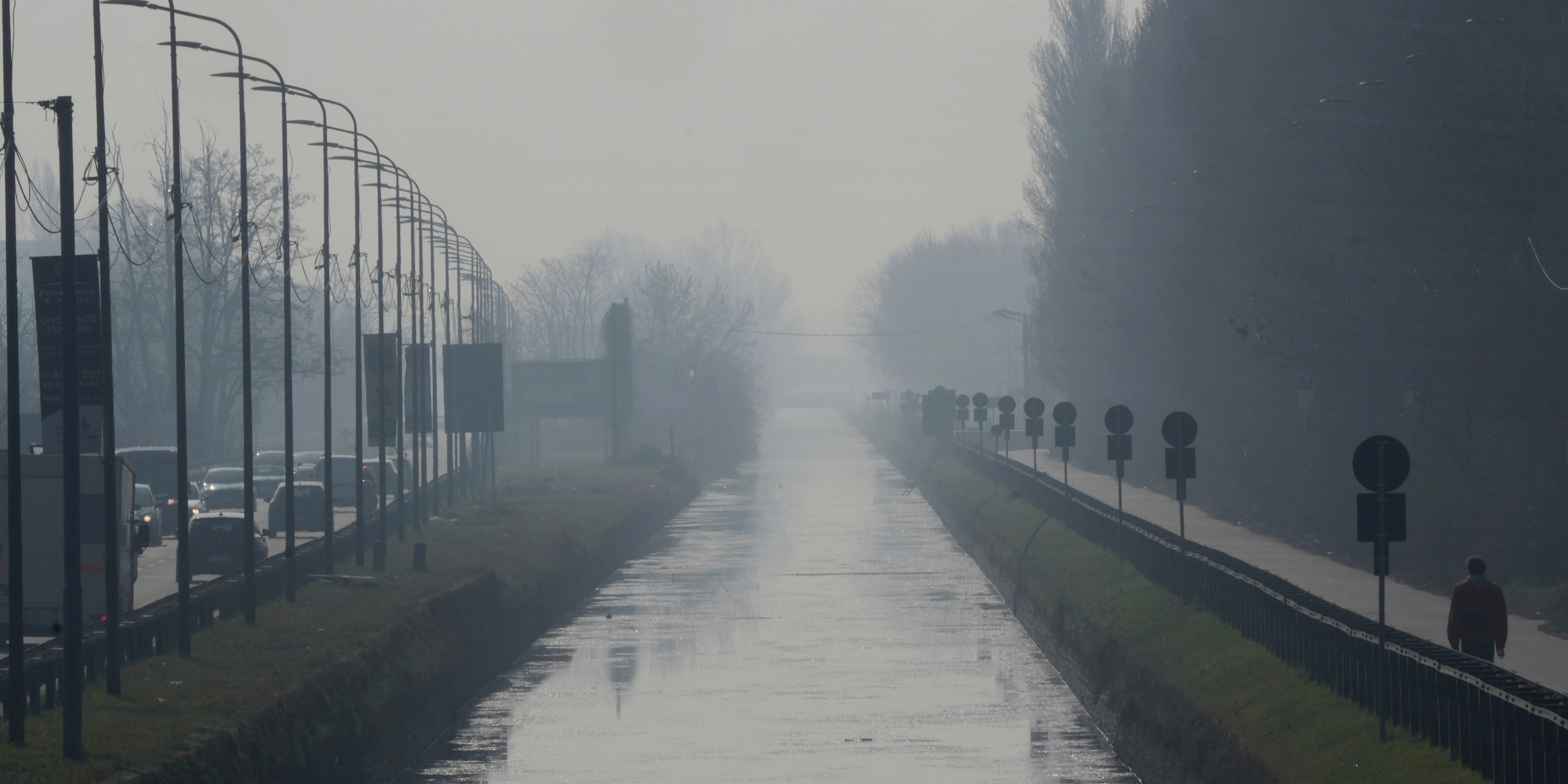 19.02.2024, Italien, Mailand: Ein Mann spaziert entlang des Kanals 
Naviglio Pavese, der in Nebel und Smog geh&uuml;llt ist. Foto: Luca Bruno/AP/dpa +++ dpa-Bildfunk +++