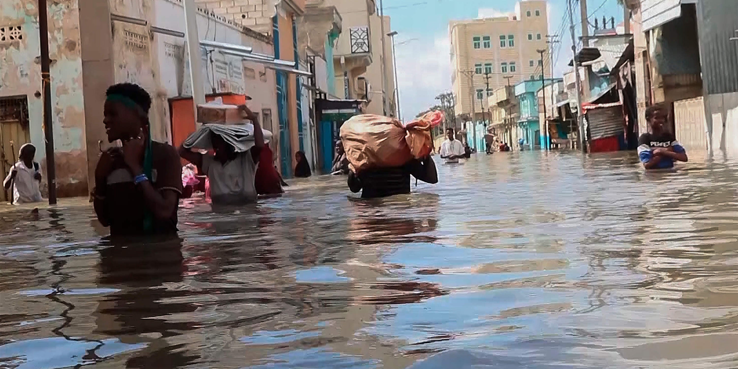 In this image made from video, men walk through floodwaters on a street in the town of Beledweyne, in Somalia, Sunday, Nov. 19, 2023. First, some families fled drought and violence. Now they say they have nowhere to hide from intense flooding as rainfall exacerbated by the weather phenomenon El Nino pummels large parts of Somalia. (AP Photo)