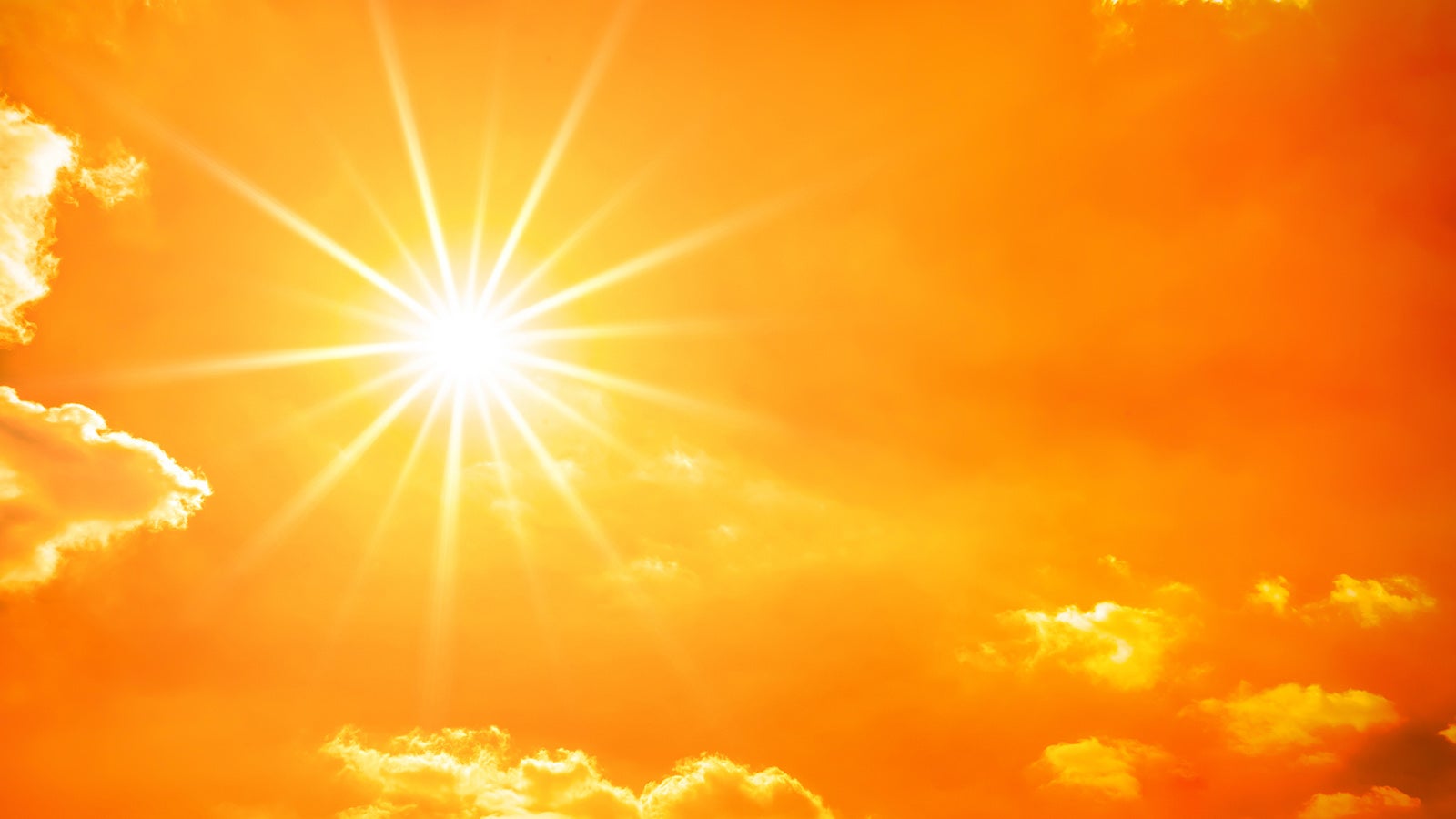 Hot summer or heat wave background, orange sky with clouds and glowing sun