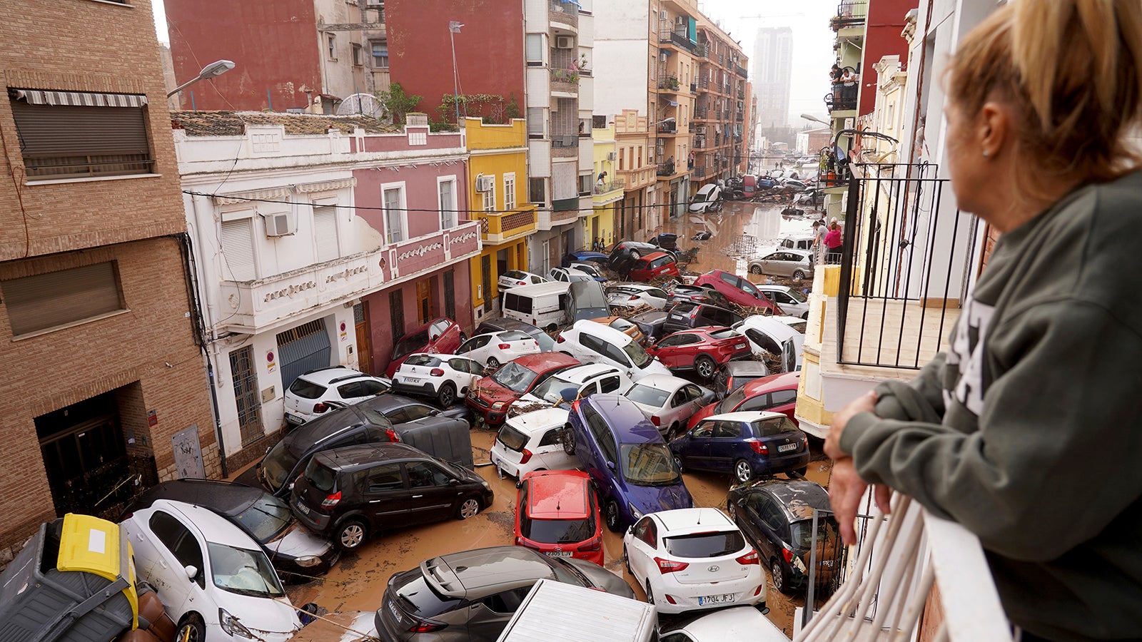 dpatopbilder - 30.10.2024, Spanien, Valencia: Eine Frau blickt von ihrem Balkon aus auf Fahrzeuge, die nach &Uuml;berschwemmungen auf der Stra&szlig;e stecken geblieben sind. Foto: Alberto Saiz/AP +++ dpa-Bildfunk +++