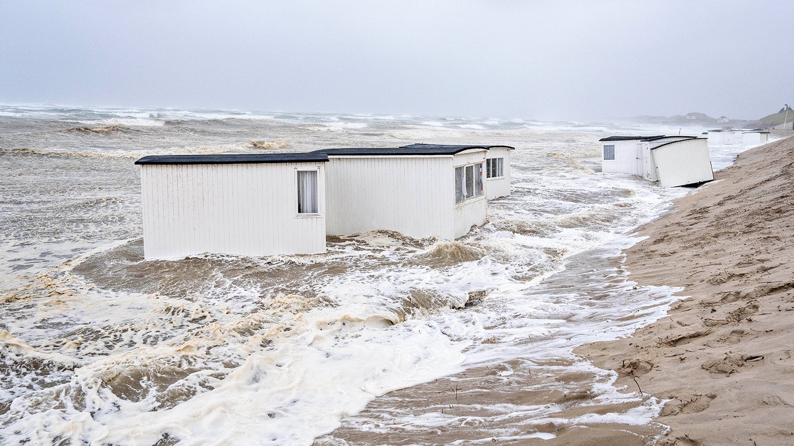 08.08.2023, D&auml;nemark, Loekken: Badeh&auml;user treiben w&auml;hrend eines Sturms im Wasser der Nordsee. Ein aufziehendes Unwetter hat in Skandinavien zu &Uuml;berschwemmungen, Br&auml;nden und Wassersch&auml;den gef&uuml;hrt. Foto: Henning Bagger/Ritzau Scanpix Foto/AP/dpa +++ dpa-Bildfunk +++