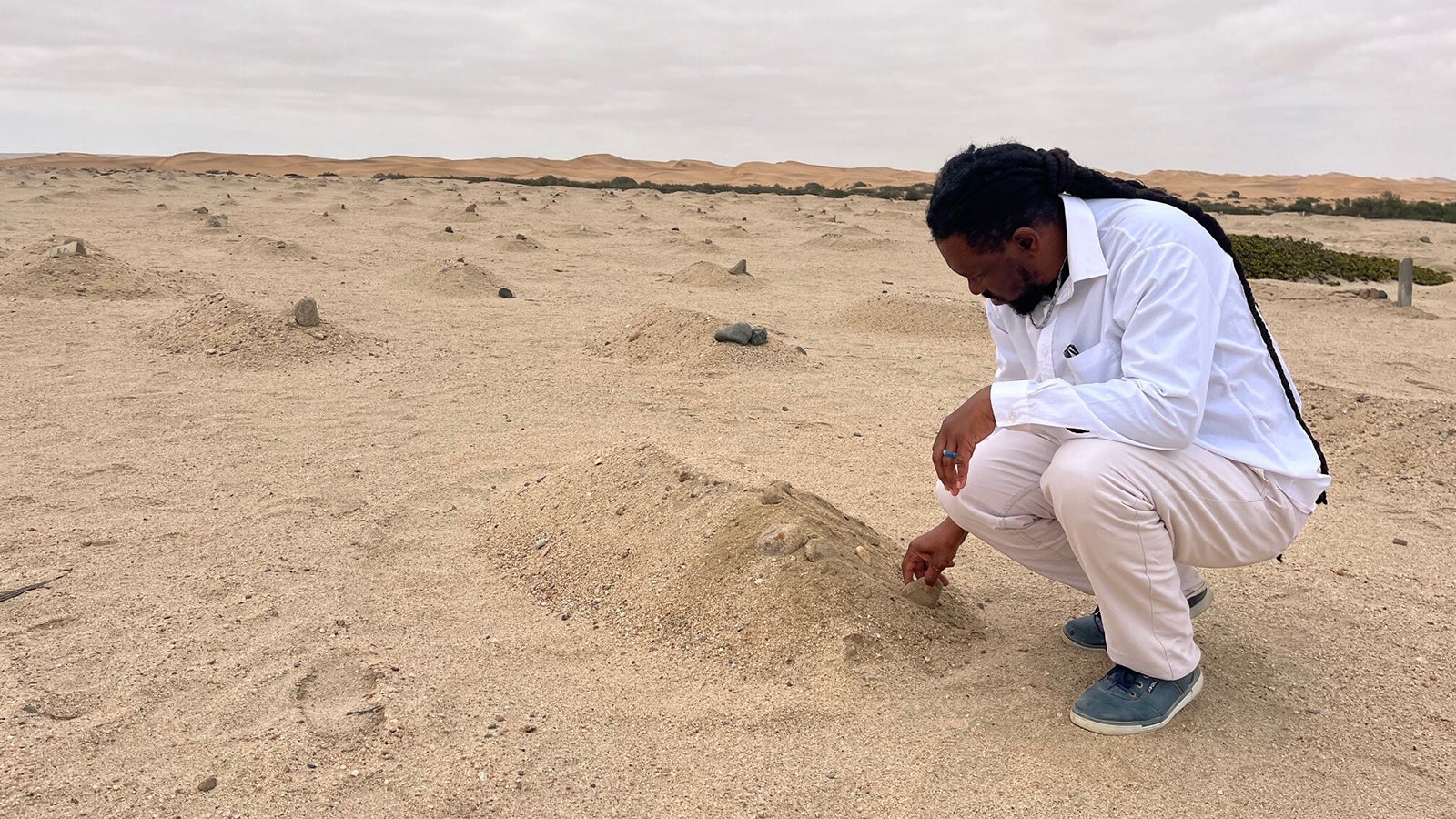 ARCHIV - 04.08.2024, Namibia, Swakopmund: Der Aktivist Laidlaw Peringanda (49) besucht unmarkierte Massengr&auml;ber von Opfern des Genozids (1904-1908) in der K&uuml;stenstadt Swakopmund, der w&auml;hrend der deutschen Kolonialzeit in Namibia ver&uuml;bt wurde. Die Gr&auml;ber liegen am Stadtrand, dort wo die W&uuml;ste beginnt. (zu dpa: &laquo;Die wohl deutscheste Stadt au&szlig;erhalb Deutschlands&raquo;) Foto: Kristin Palitza/dpa +++ dpa-Bildfunk +++