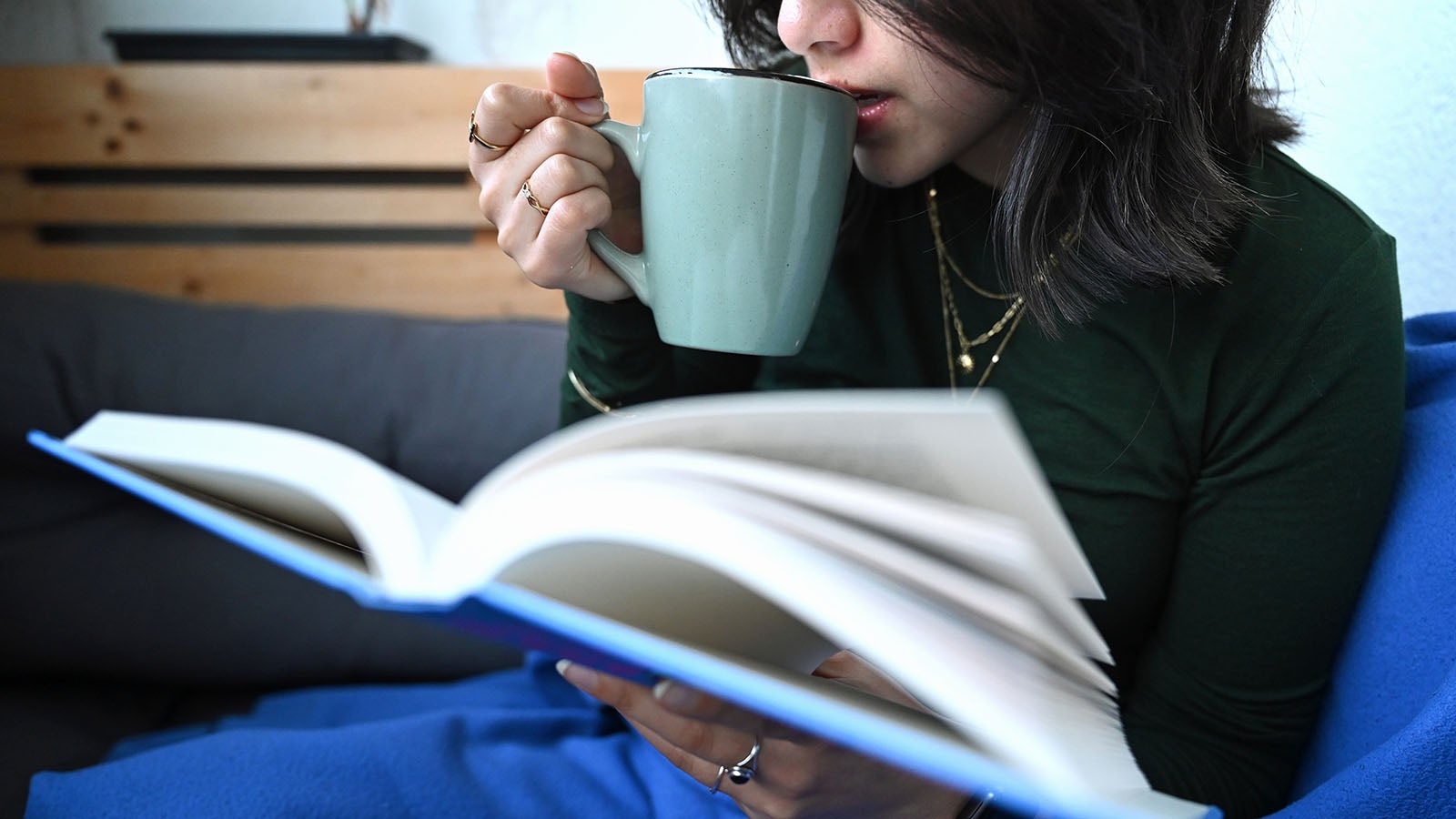 SYMBOLBILD - 02.01.2026, Berlin: Eine Frau liest ein Buch w&auml;hrend sie aus einer Tasse Kaffee trinkt. Mit der Zeitumstellung bleibt abends mehr Zeit f&uuml;r Freizeitaktivit&auml;ten.  (zu dpa: &laquo;Mehr Licht, mehr Leben: Tipps f&uuml;r die Extra-Stunde am Abend&raquo;) Foto: Elisa Schu/dpa +++ dpa-Bildfunk +++