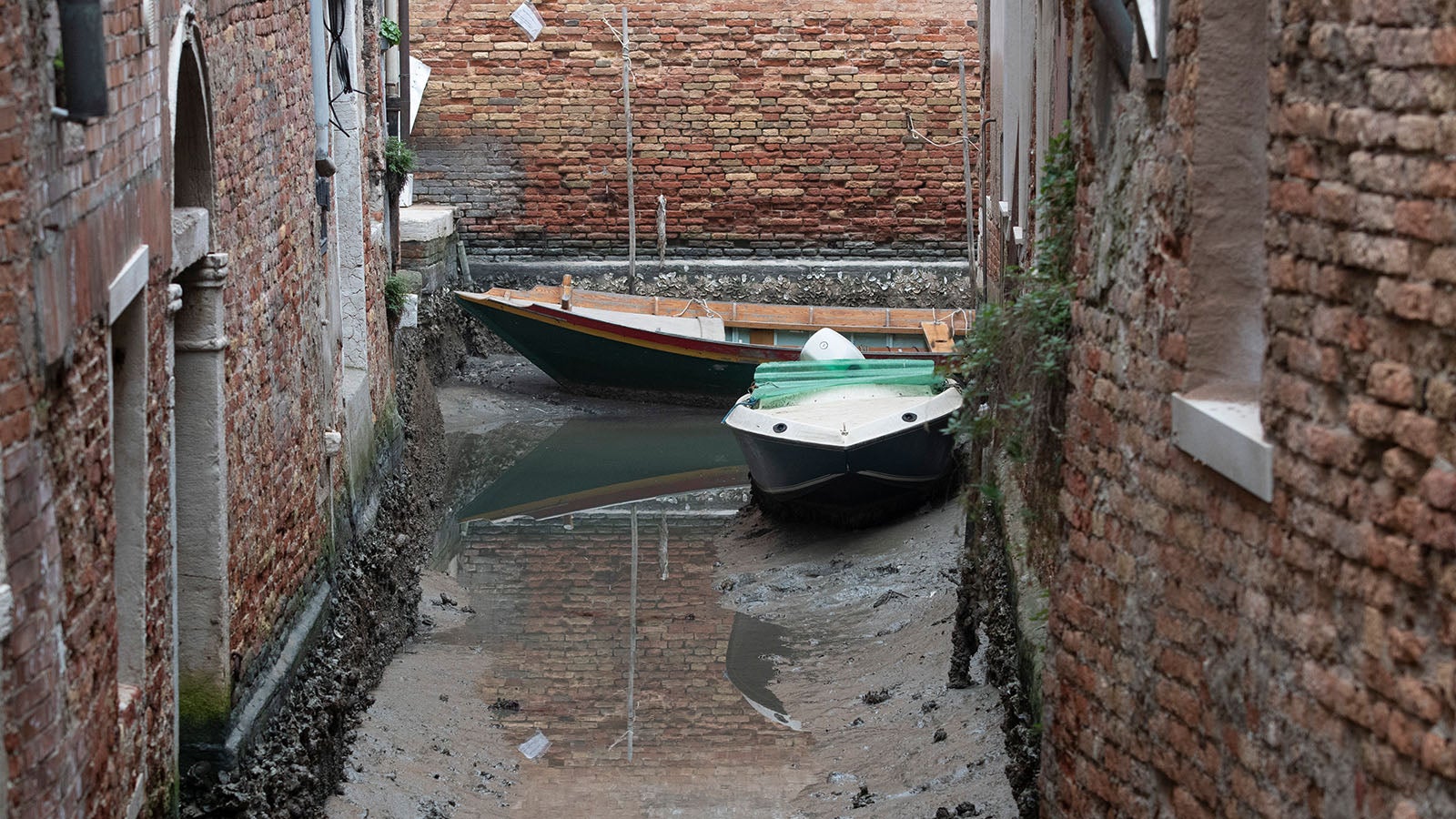 Boats are docked along a dried canal during a low tide in Venice, Italy, Tuesday, Feb. 21, 2023. Some of&nbsp;Venice's secondary canals have practically dried up lately due a prolonged spell of low tides linked to a lingering high-pressure weather system. (AP Photo/Luigi Costantini)