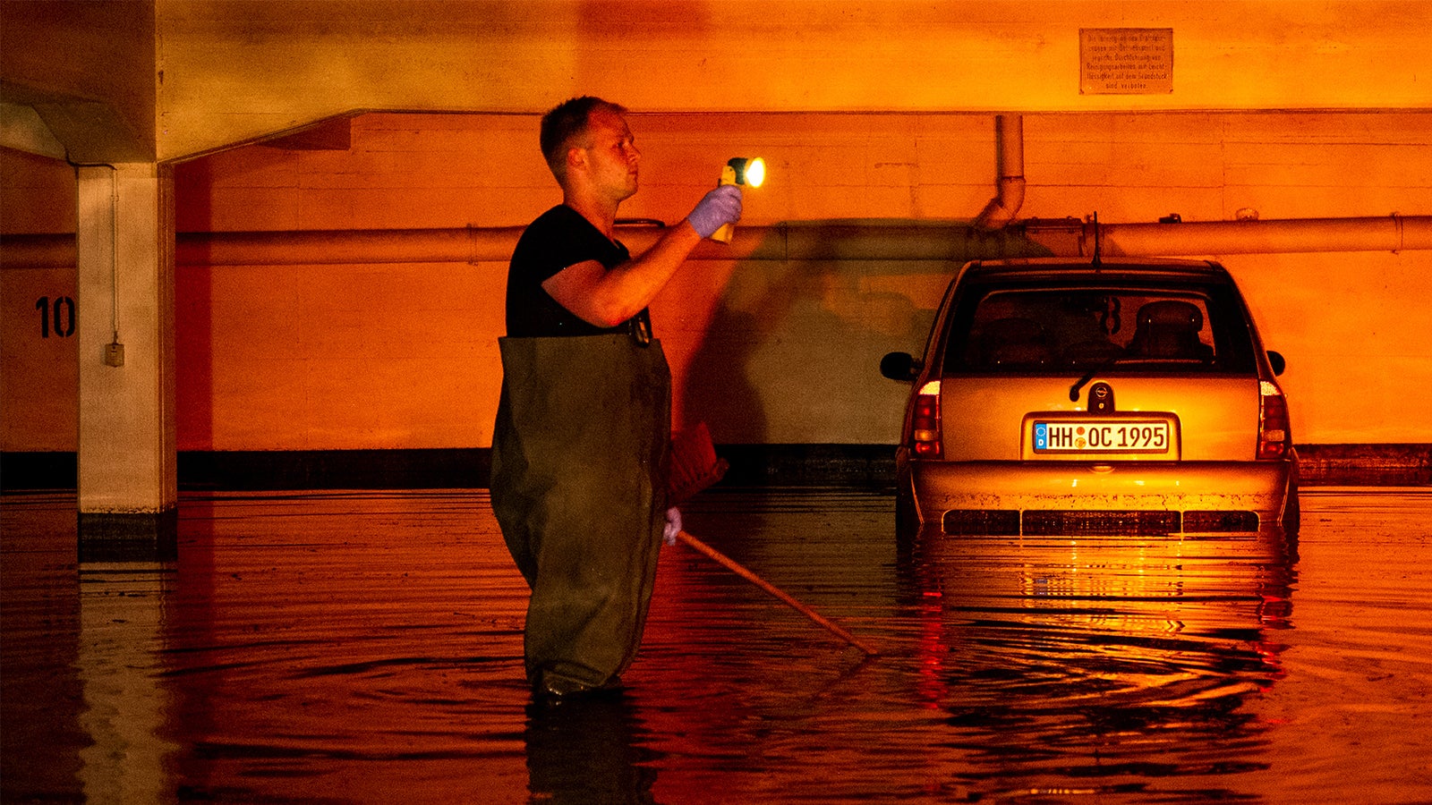 Ein Auto steht im Stadtteil Billstedt in einer durch Starkregen &uuml;berfluteten Tiefgarage und wird vom Licht einer Warnblinkanlage angeleuchtet. Foto: Daniel Bockwoldt/dpa
