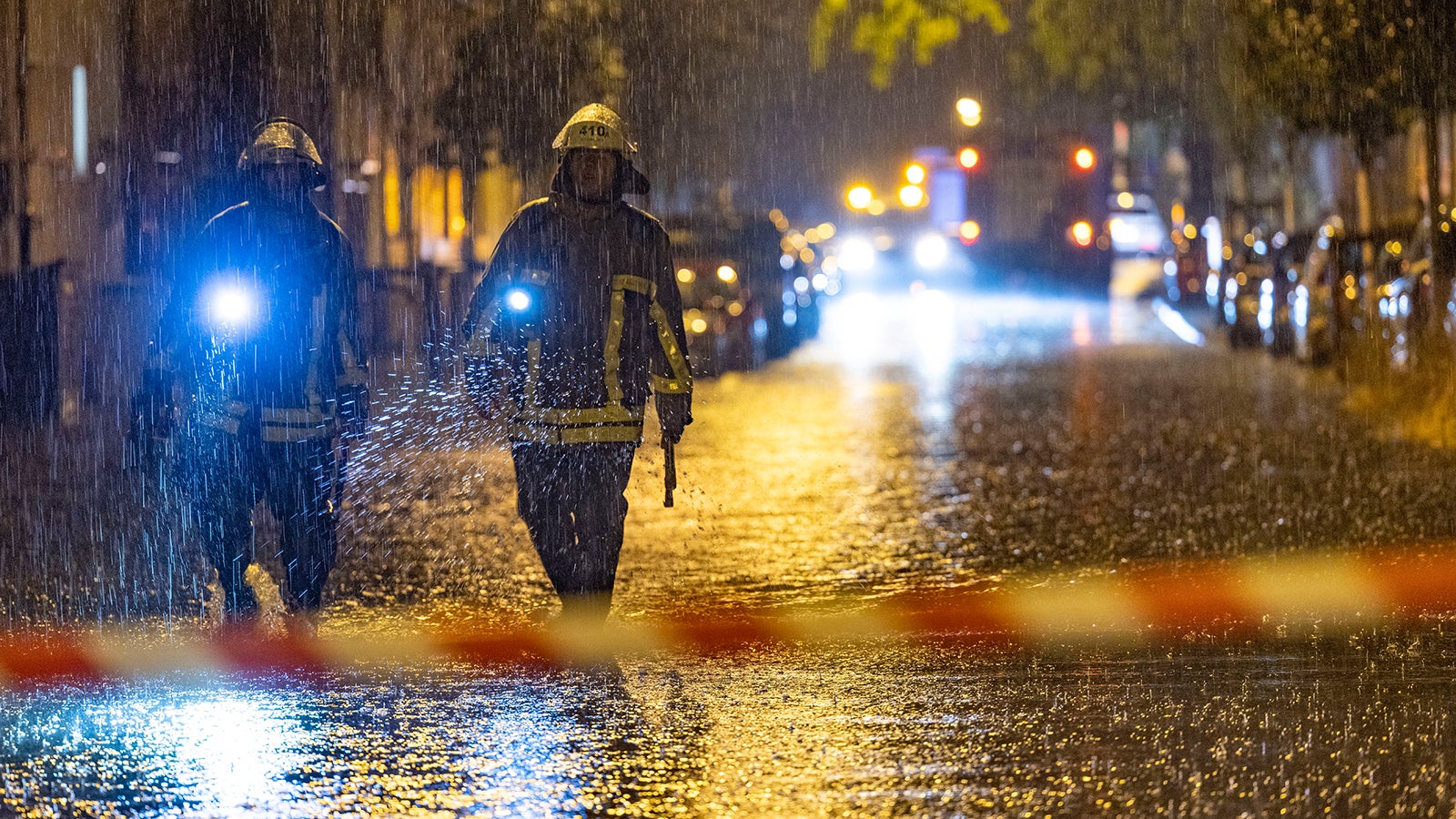 dpatopbilder - 23.06.2023, Duisburg: Feuerwehrleute suchen auf einer &uuml;berfluteten Stra&szlig;e in Duisburg nach Gullydeckeln. Mit teils heftigen Regenf&auml;llen und Gewittern hat ein Unwetter Nordrhein-Westfalen am Donnerstag erreicht. Foto: Christoph Reichwein/dpa +++ dpa-Bildfunk +++