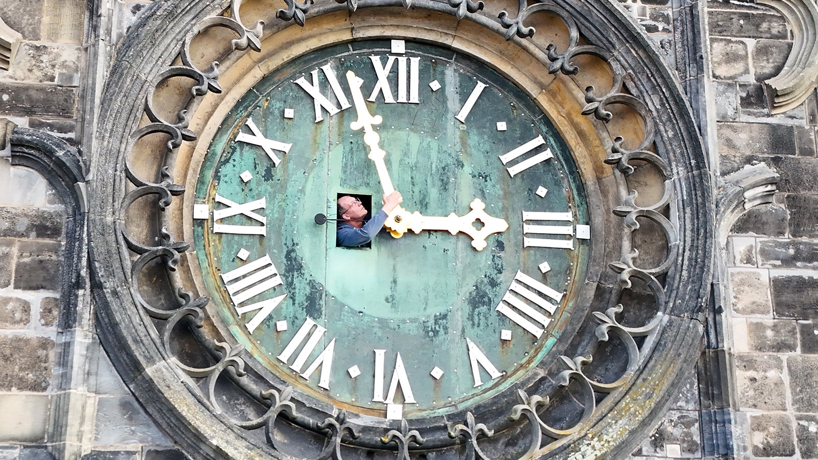 dpatopbilder - 20.03.2026, Sachsen-Anhalt, Magdeburg: Hans Studte, Domk&uuml;ster vom Magdeburg Dom, kontrolliert durch eine Luke die Zeiger der westlichen Turmuhr.(Aufnahme mit Drohne) Die Uhr stammt &uuml;brigens aus dem Jahr 1860 und l&auml;uft voll mechanisch. Am n&auml;chsten Wochenende beginnt in Deutschland wieder die Sommerzeit und die Uhren werden um eine Stunde vorgedreht. Foto: Peter Gercke/dpa +++ dpa-Bildfunk +++