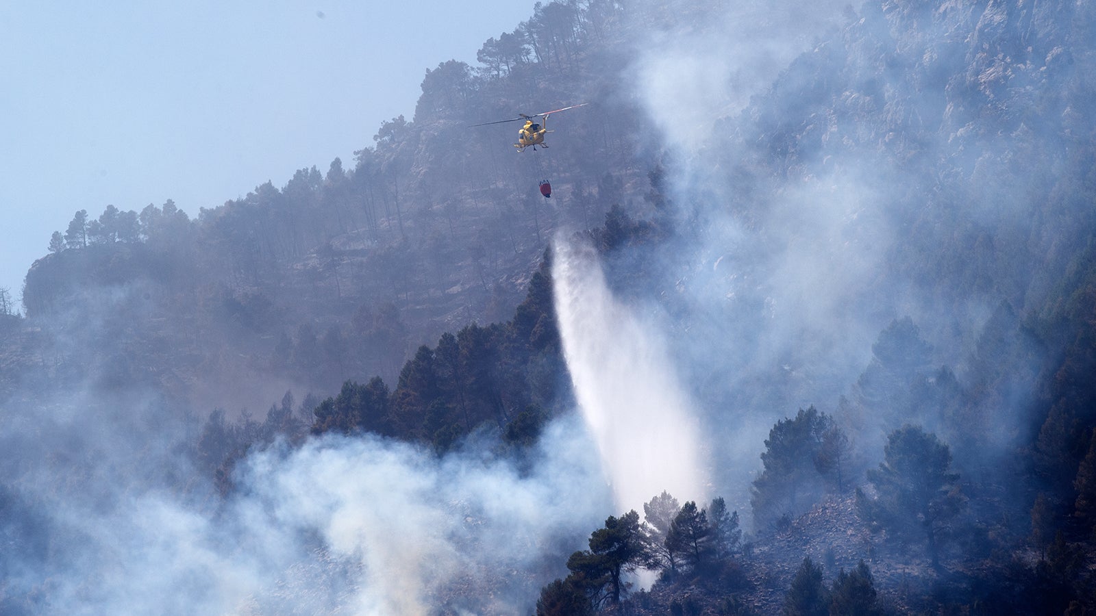 26.03.2023, Spanien, Montanjejos: Ein Hubschrauber wirft Wasser ab, um den Waldbrand in Montanejos, Castellon de la Plana, Spanien, zu l&ouml;schen. Mehr als 1.500 Menschen wurden evakuiert, da in der ostspanischen Provinz Castellon ein gro&szlig;er Waldbrand w&uuml;tet, der den fr&uuml;hen Beginn der nationalen Feuersaison bei gro&szlig;er Trockenheit markiert. Nach Angaben der &ouml;rtlichen Beh&ouml;rden hat das Feuer rund 3 000 Hektar Land verschlungen. Foto: Alberto Sa&iacute;z/ap/dpa +++ dpa-Bildfunk +++
