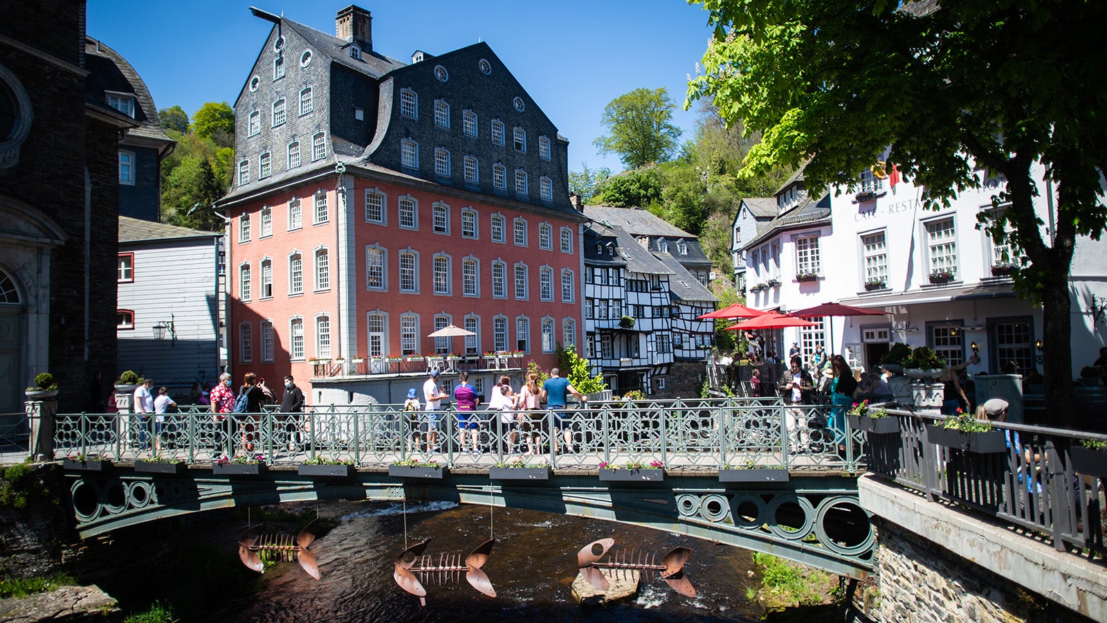 Menschen stehen auf einer Br&uuml;cke vor dem so genannten &bdquo;Roten Haus&ldquo;. Meteorologen sagen f&uuml;r den heutigen Sonntag und die kommenden Tage viel Sonne und warme Temperaturen voraus. (zu dpa: &laquo;Lage bei Monschau angespannt - Waldbrand r&uuml;ckt n&auml;her&raquo;)