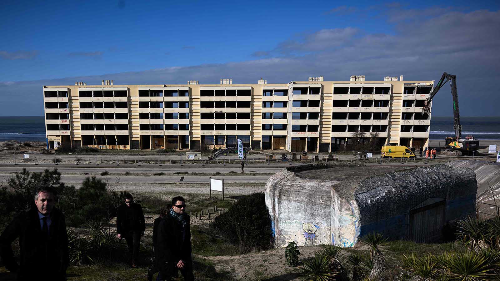 03.02.2023, Frankreich, Soulac-Sur-Mer: Christophe Bechu (l), Minister f&uuml;r &ouml;kologischen Wandel und territorialen Zusammenhalt in Frankreich, entfernt sich vom Ort des Abrisses des Signal-Geb&auml;udes. Das Geb&auml;ude wurde 2014 von den franz&ouml;sischen Beh&ouml;rden evakuiert, um einen Einsturz aufgrund der Meeresfluten zu verhindern, und ist seitdem zu einem Symbol f&uuml;r die K&uuml;stenerosion geworden. Foto: Philippe Lopez/AFP/dpa +++ dpa-Bildfunk +++