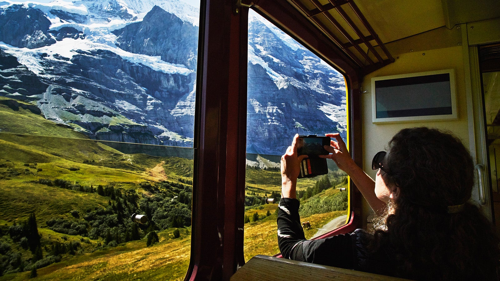 Woman taking photo with smartphone of Jungfrau while riding in train