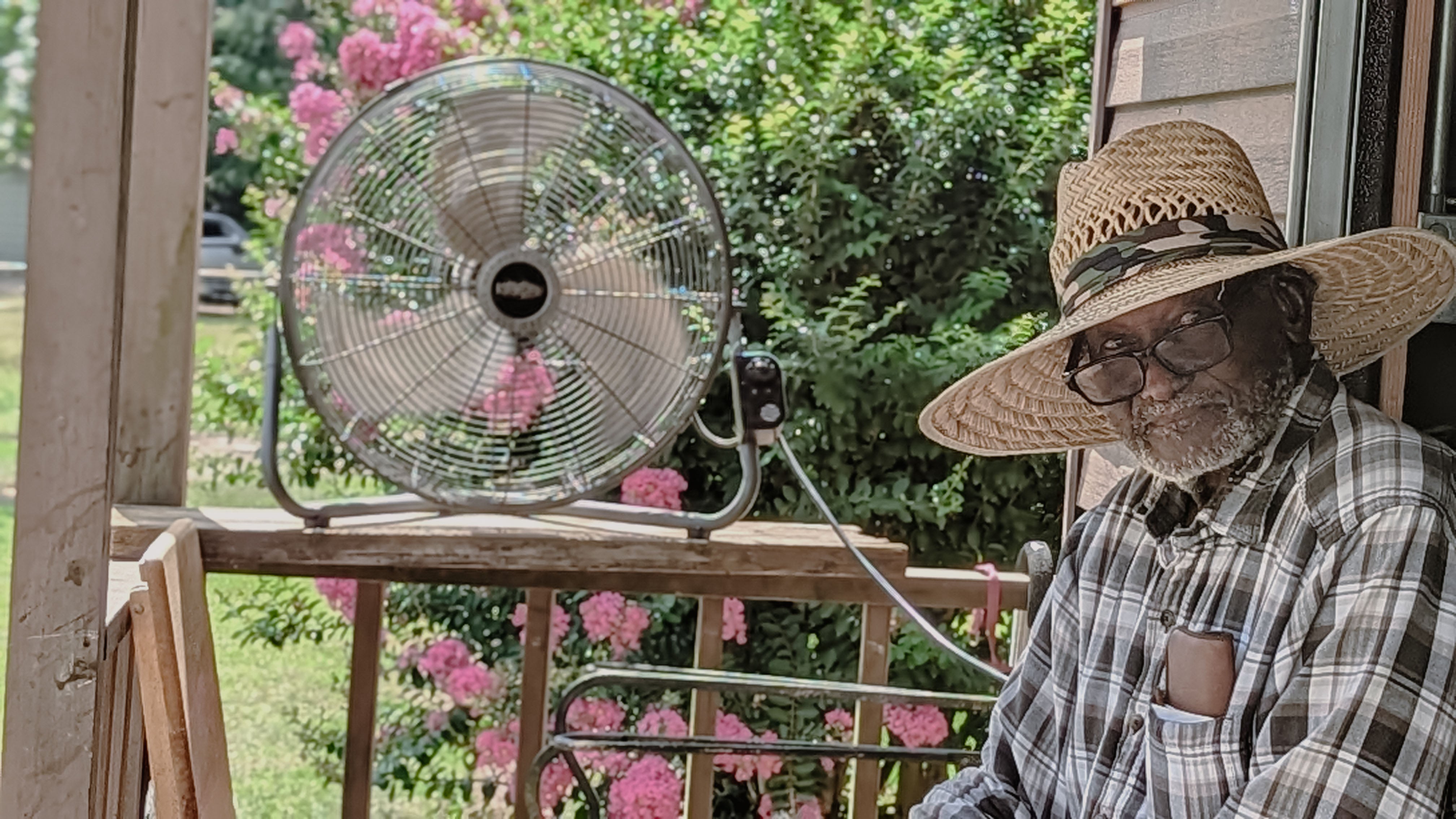 Portrait of an Elderly African American man using an outdoor electric fan to cool off