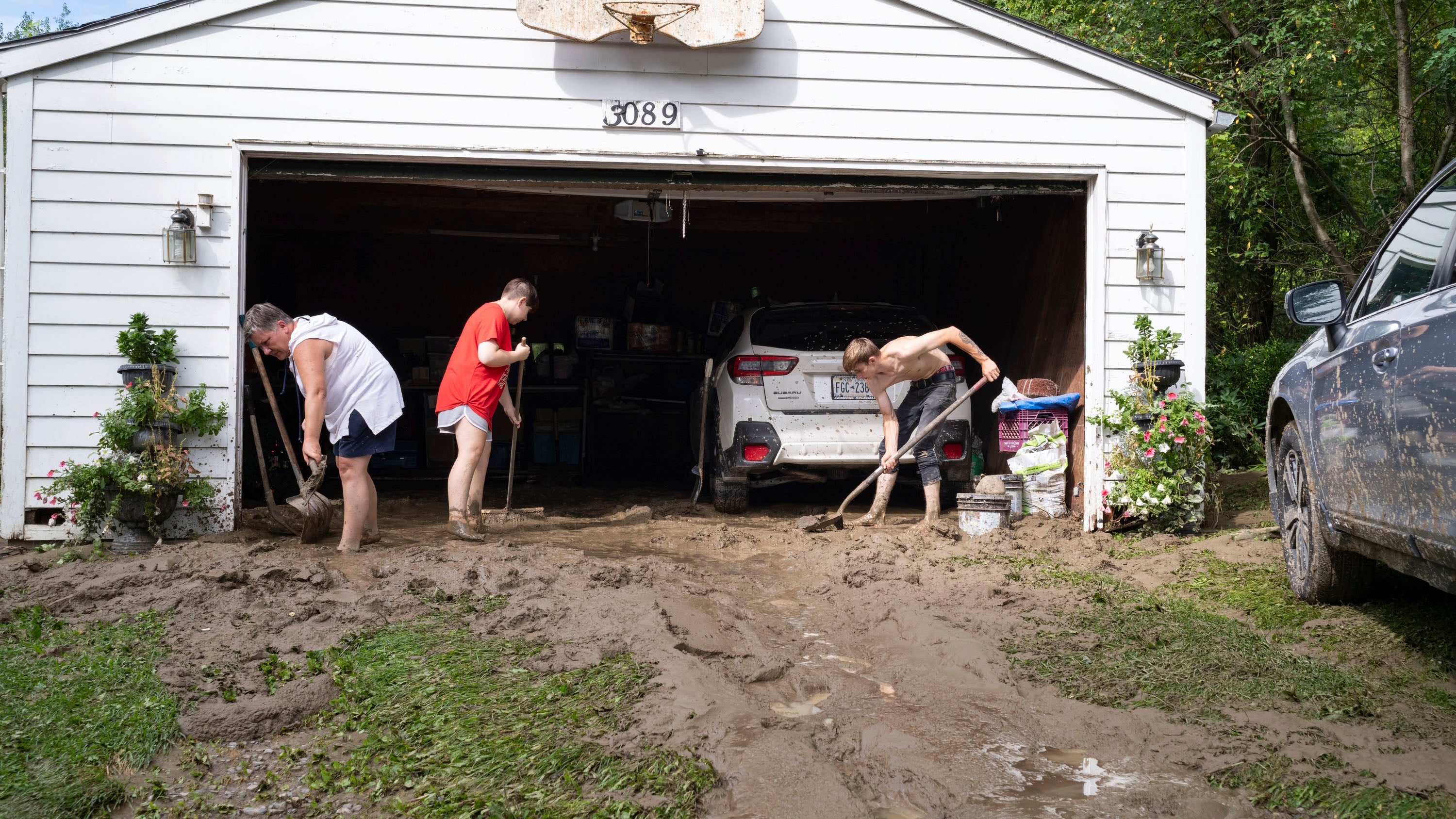 Ann Farkas, left, works with her daughter Alex Farkas and family friend Damian Hartman as they clean up the Farkas home in Canisteo, N.Y., Friday, Aug. 9, 2024, after remnants of Tropical Storm Debby swept tough the area, creating flash flood conditions in some areas. (AP Photo/Craig Ruttle)