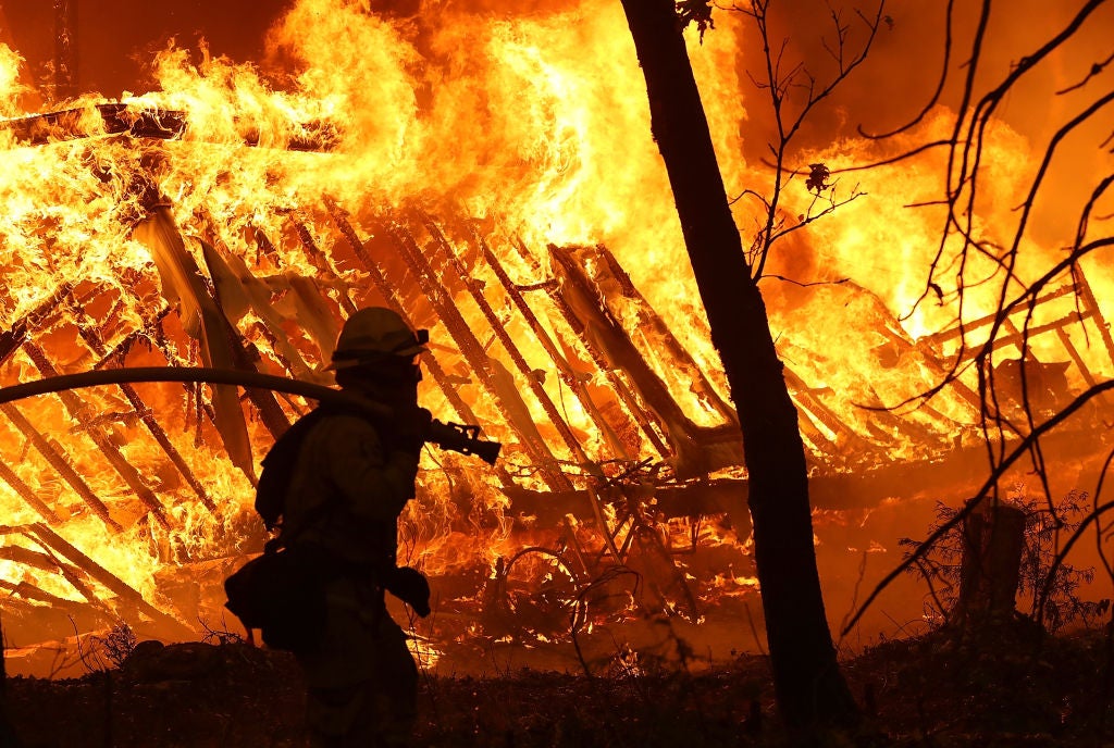 MAGALIA, CA - NOVEMBER 09:  A Cal Fire firefighter monitors a burning home as the Camp Fire moves through the area on November 9, 2018 in Magalia, California. Fueled by high winds and low humidity, the rapidly spreading Camp Fire ripped through the town of Paradise and has quickly charred 70,000 acres and has destroyed numerous homes and businesses in a matter of hours. The fire is currently at five percent containment.  (Photo by Justin Sullivan/Getty Images)