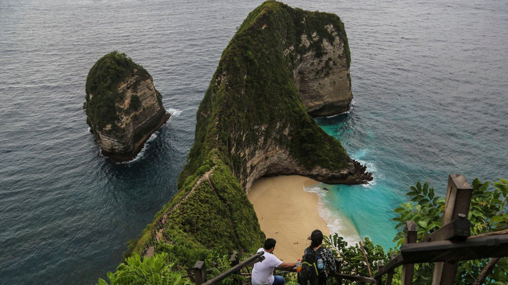 Wisatawan berjalan menuruni tangga menuju Pantai Kelingking, di Nusa Penida, Bali, Indonesia, pada 9 Maret 2020. Lanskap destinasi wisata populer ini berubah drastis dengan dibangunnya lift kontroversial setinggi hampir 600 kaki.