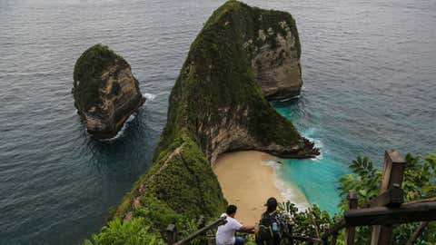 Wisatawan berjalan menuruni tangga menuju Pantai Kelingking, di Nusa Penida, Bali, Indonesia, pada 9 Maret 2020. Lanskap destinasi wisata populer ini berubah drastis dengan dibangunnya lift kontroversial setinggi hampir 600 kaki.