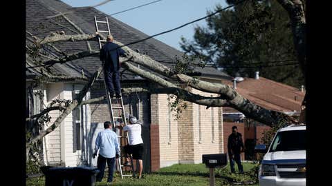 Residents clear a tree that fell on a roof after Hurricane Zeta on Oct. 29, 2020, in Chalmette, La. A record seven hurricanes have hit the gulf coast in 2020 bringing prolonged destruction to the area. (Sandy Huffaker/Getty Images)