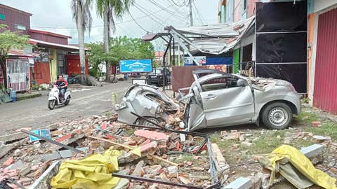 A destroyed car sits amongst debris on the side of a street in Mamuju on Jan. 15, 2021, after a 6.2-magnitude earthquake rocked Indonesia's Sulawesi island. (Mawardi/AFP via Getty Images)