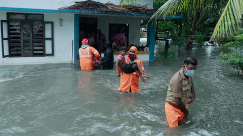 Police and rescue personnel evacuate local residents from a flooded house in a coastal area after heavy rains under the influence of Cyclone Tauktae in Kochi on May 14, 2021. (Arunchandra Bose/AFP via Getty Images)