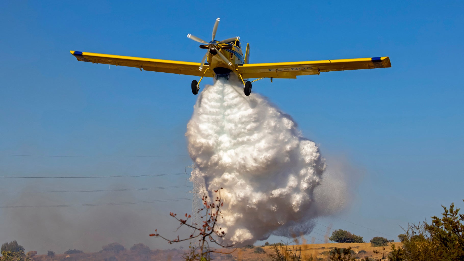 A Spanish Air Tractor AT-802A firefighting plane dumps water on the southern slopes of the Troodos mountains close to Agioi Vavatsinias village as a major fire continued to burn on the Mediterranean island of Cyprus on July 4, 2021. (GEORGIO PAPAPETROU/AFP via Getty Images)