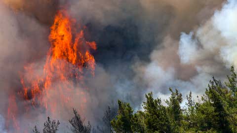 Smoke and flames rise as intervention by air and land continues to control a wildfire that broke out overnight in a forest in the Marmaris district of Mugla province in southern Turkey, on June 22, 2022. Air intervention continues with 20 helicopters and 14 planes. (Mehmet Emin Menguarslan/Anadolu Agency via Getty Images)