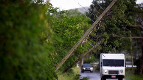 Cars drive under precariously knocked-down power lines on road PR-303 on Sept. 20, 2022, in Lajas, Puerto Rico. The island awoke to a general island power outage after Hurricane Fiona struck on Sunday. (Jose Jimenez/Getty Images)