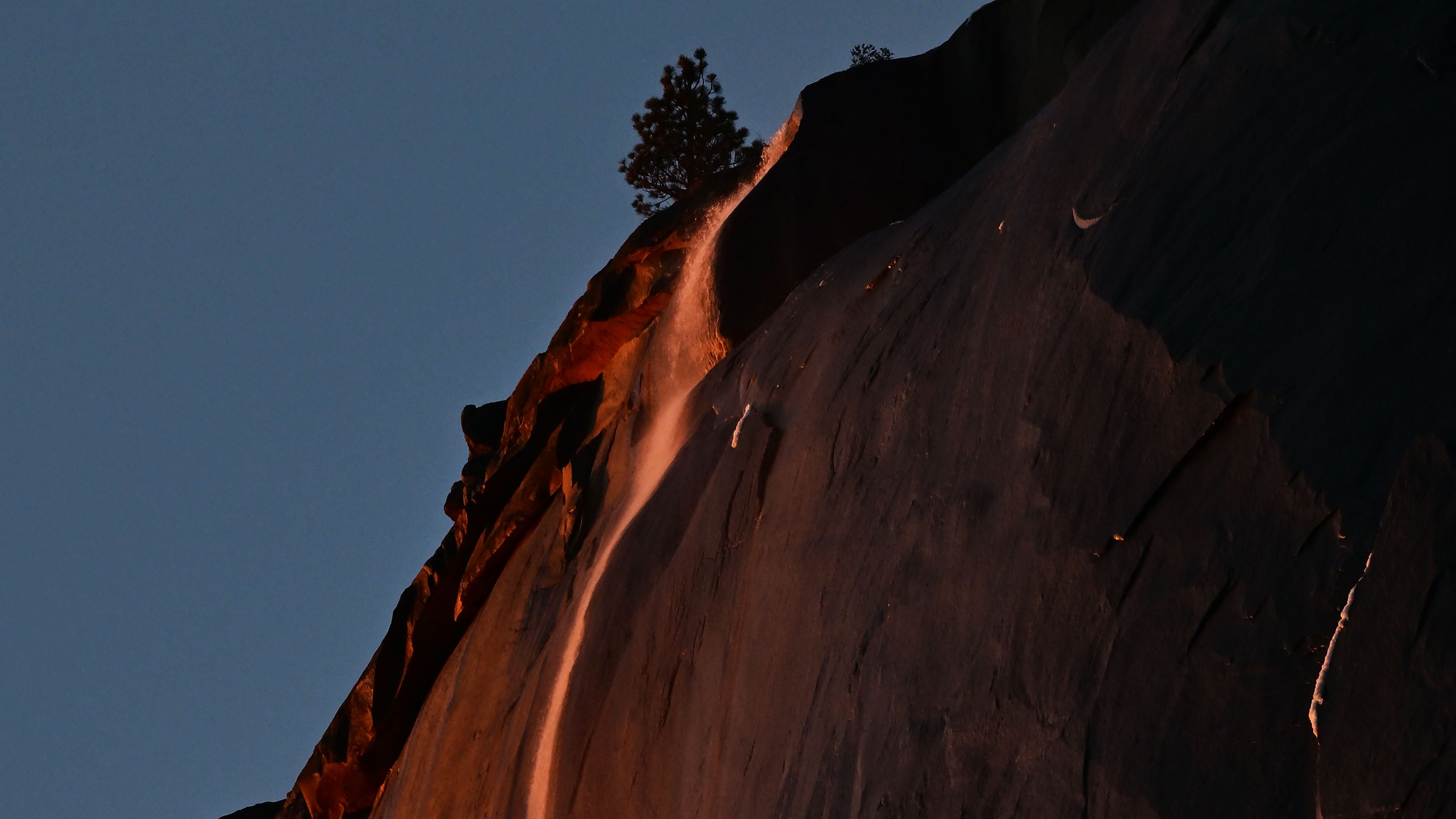 Water flowing off Horsetail Fall glows orange while backlit from the setting sun during the "Firefall" phenomenon in Yosemite National Park, Calif., on Feb. 15, 2023. On rare occasions every year from mid- to late February the unique lighting effect at Horsetail Falls can be seen when the the sky is clear and water is flowing. (Frederic J. Brown/AFP via Getty Images)