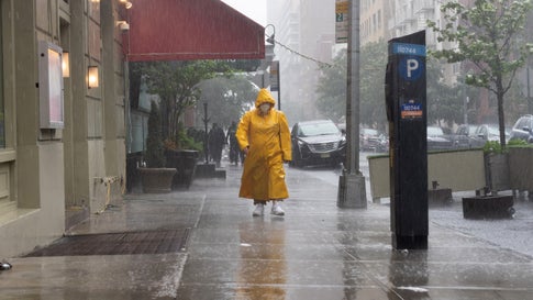 A person wearing a mask and a raincoat walks in the rain during Tropical Storm Fay as the city moves into Phase 3 of re-opening following restrictions imposed to curb the coronavirus pandemic on July 9, 2020, in New York City. Phase 3 is the third of four-phased stages designated by the state. (Alexi Rosenfeld/Getty Images)