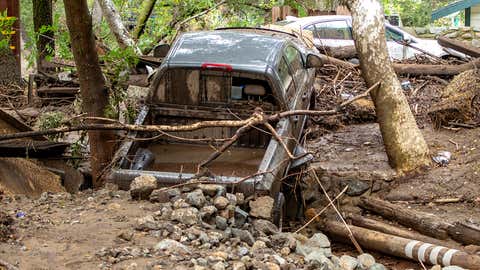 A pickup truck that was washed down a creek in Silverado Canyon in Silverado, Calif., sits wedged against a driveway with the creek flowing underneath following heavy rain early on Wednesday morning, March 10. 2021. The storm caused flash flooding and mud slides with cars and debris washed down the creeks as people that stayed behind try to dig out before more rain falls in the area. (Mark Rightmire/MediaNews Group/Orange County Register via Getty Images)