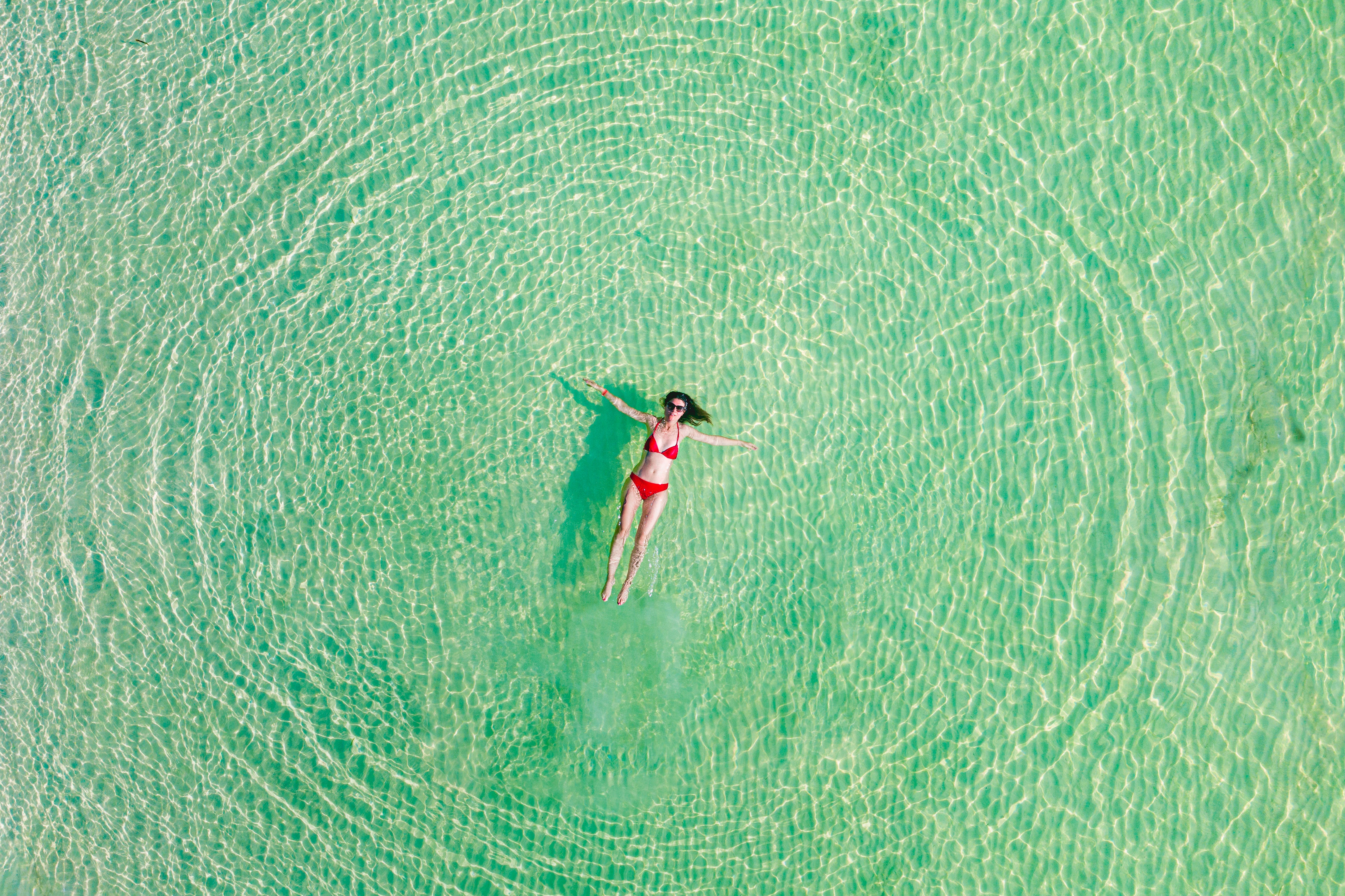 A woman floats in clear water wearing a red bikini. (Marco Bottigelli / Getty Images)