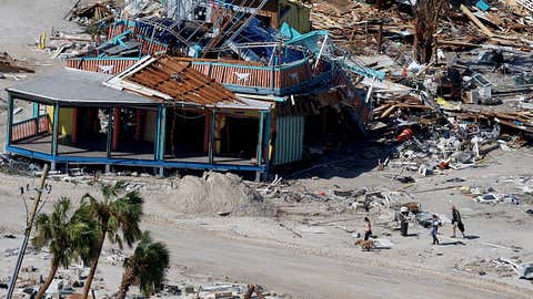 FORT MYERS BEACH, FLORIDA - SEPTEMBER 29: People walk past a building destroyed as Hurricane Ian passed through the area on September 29, 2022 in Fort Myers Beach, Florida. The hurricane brought high winds, storm surge and rain to the area causing severe damage. (Photo by Joe Raedle/Getty Images)