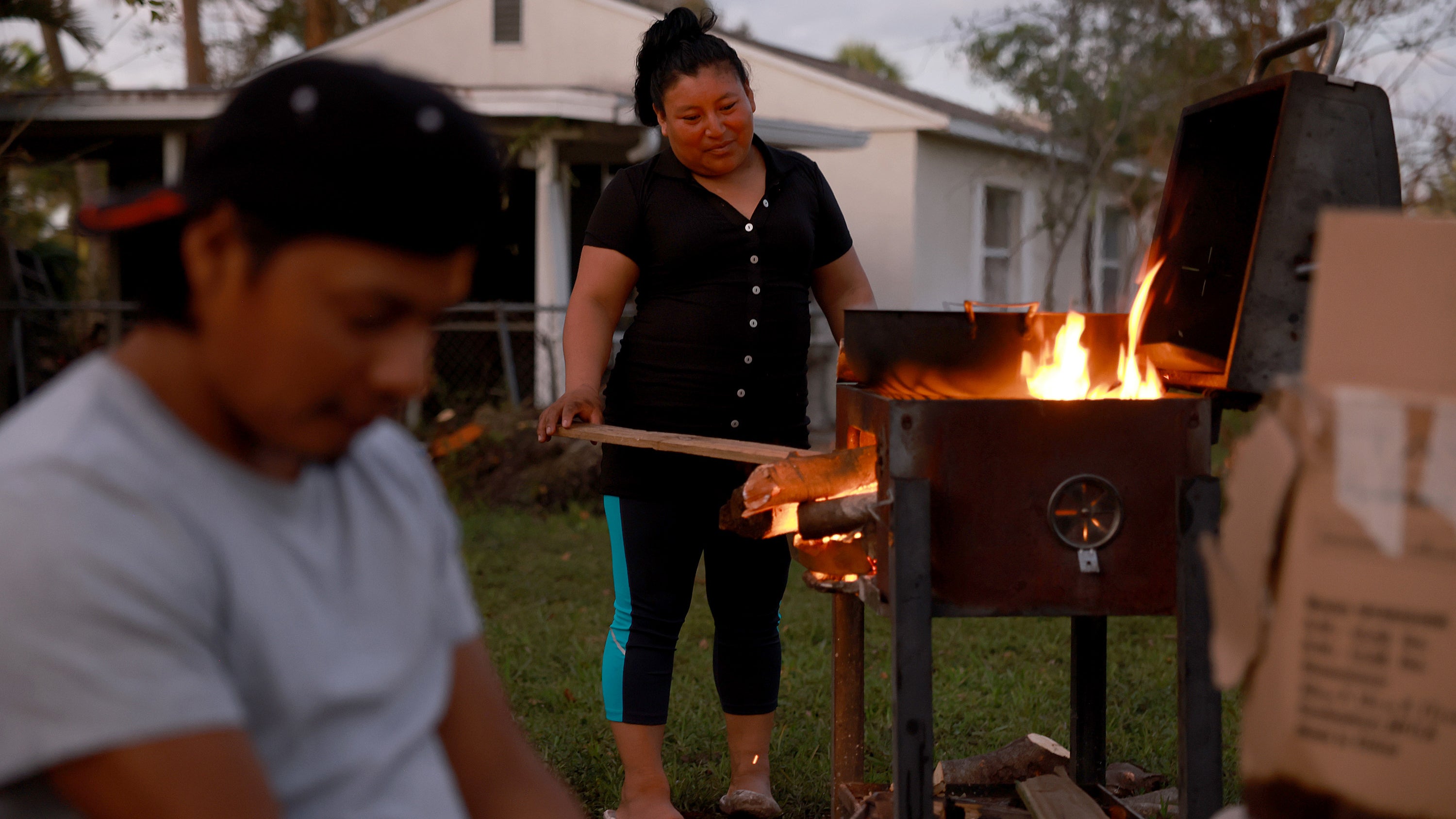 FORT MYERS, FLORIDA - OCTOBER 07: Anna Vincente cooks a ramen and egg dinner over a wood fire because her house has no electricity on October 07, 2022 in Fort Myers, Florida. Her family uses a generator to light the lamp so they can have light outside. Many homes continue to lack water and electricity over a week after Hurricane Ian brought high winds, storm surges, and rain to the area, causing severe damage. (Photo by Joe Raedle/Getty Images)