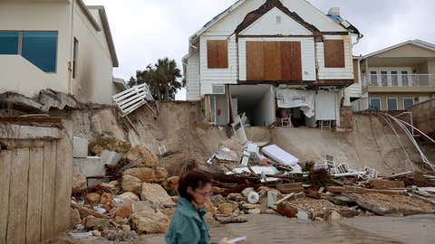 Homes are partially toppled onto the beach after Hurricane Nicole came ashore on Nov. 10, 2022, in Daytona Beach, Fla.  Nicole came ashore as a Category 1 hurricane before weakening to a tropical storm as it moved across the state. (Joe Raedle/Getty Images)