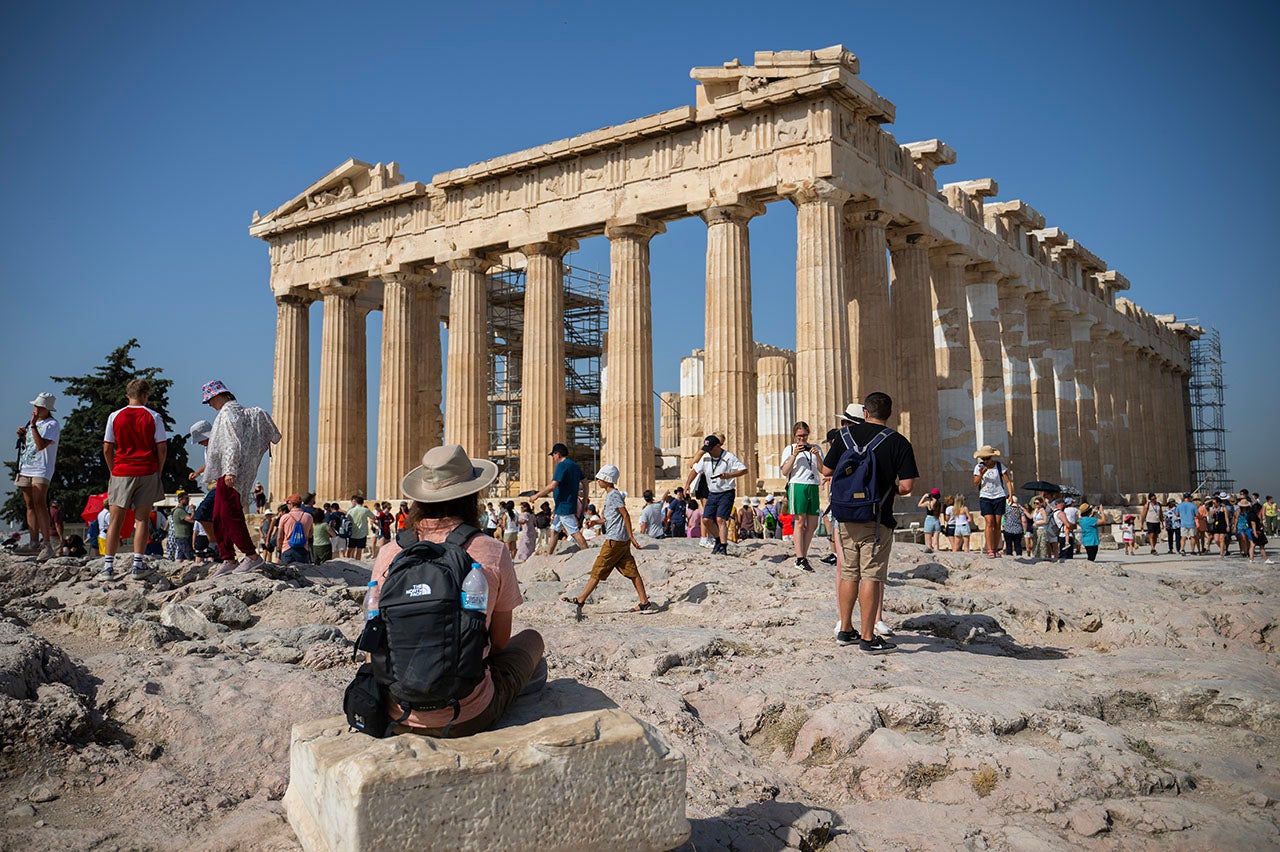 Tourists walk around the Acropolis during their visit to the Parthenon temple on a hot July 14, 2023. The Ministry of Culture has decided to close the archaeological site during the hottest hours of the day, from noon to 5 p.m., as Greece is currently experiencing a heat wave. (Angelos Tzortzinis/picture alliance via Getty Images)