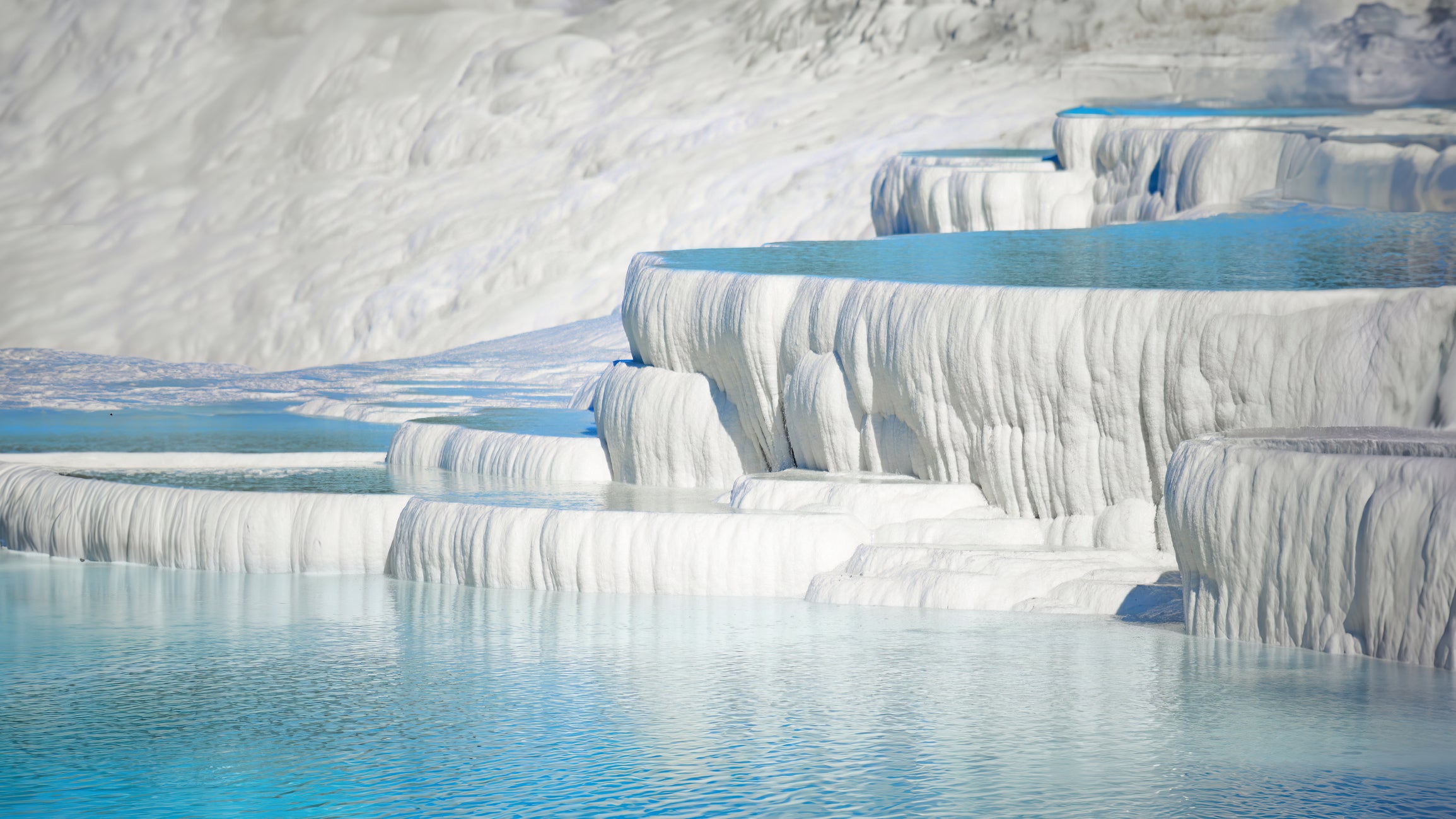 Pamukkale is a natural site in Denizli Province in southwestern Turkey. The area is famous for a carbonate mineral left by the flowing of thermal spring water.