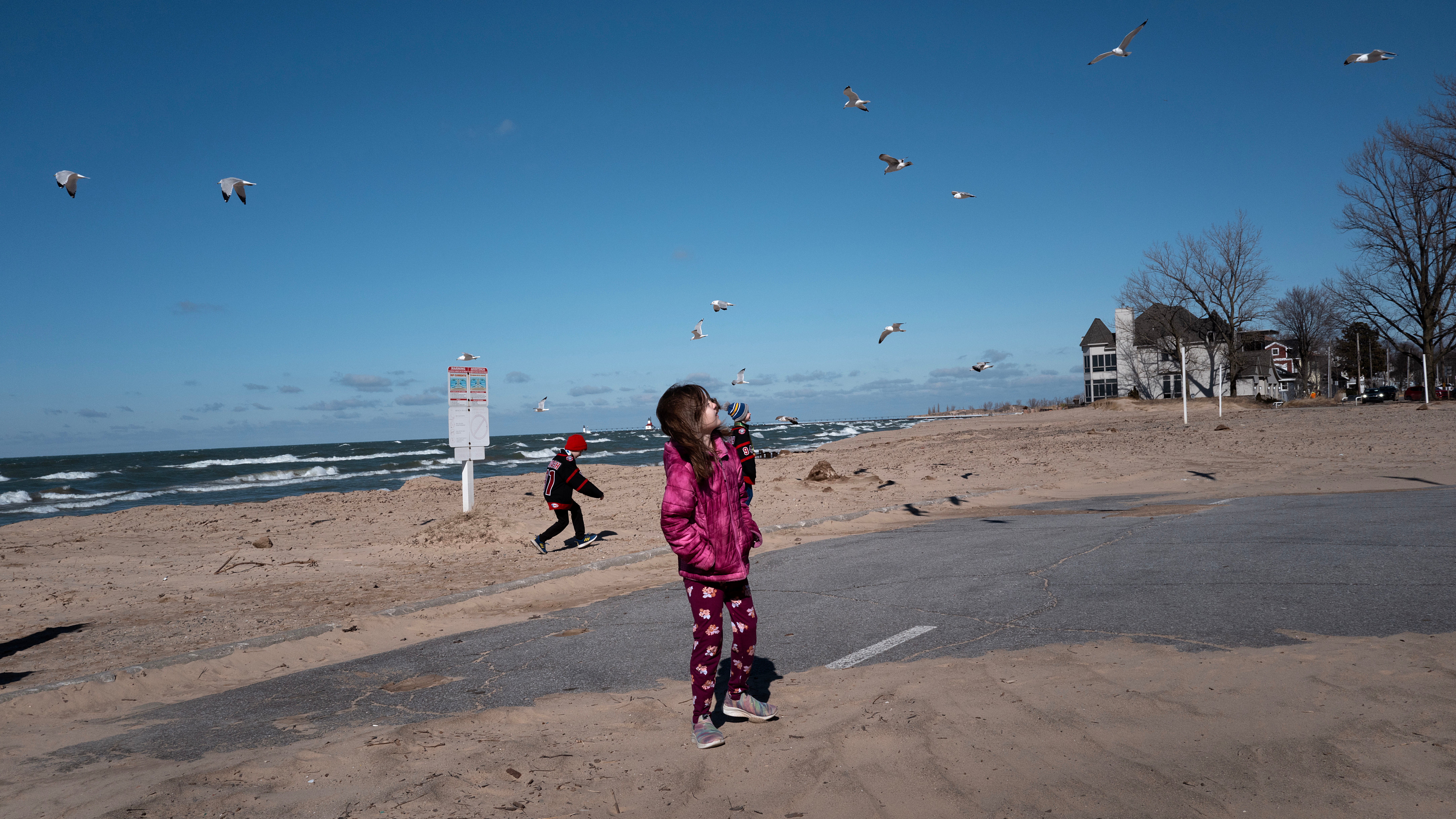 WHITING, INDIANA - FEBRUARY 18: Children play along the Lake Michigan shoreline on February 18, 2024 in Whiting, Indiana. The Great Lakes shorelines have historically been ice-covered this time of year, but this winter's warm weather has led to the lowest ice cover over the lakes system since record keeping began in 1973. The loss of ice on the lakes is part of a decades-long trend which has seen the coverage drop by about 5% a year since the 1970s.  (Photo by Scott Olson/Getty Images)