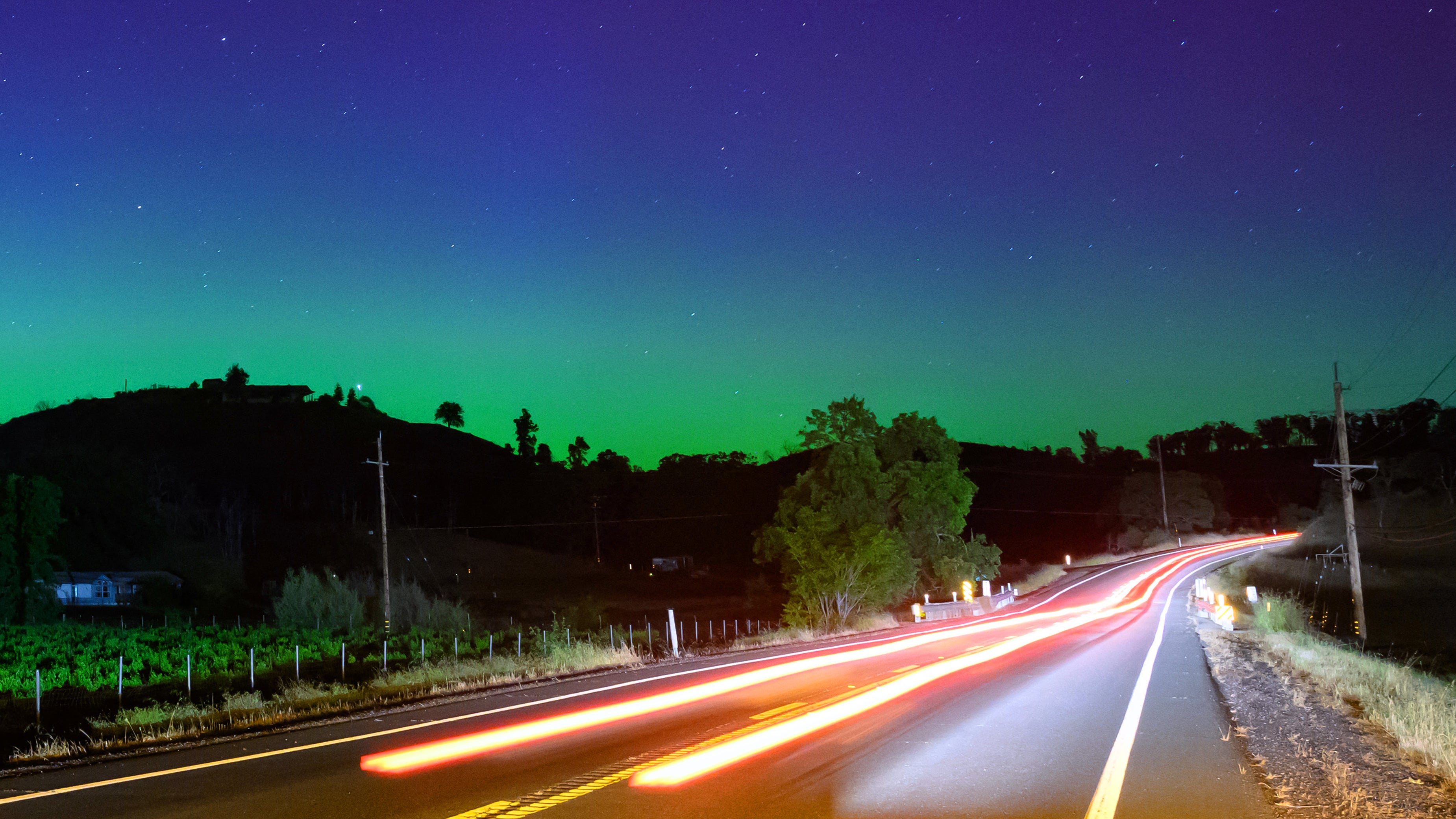 Northern lights or aurora borealis illuminate the night sky along a highway north of San Francisco in Middletown, California on May 11, 2024. The most powerful solar storm in more than two decades struck Earth, triggering spectacular celestial light shows from Tasmania to Britain -- and threatening possible disruptions to satellites and power grids as it persists into the weekend. (Photo by JOSH EDELSON / AFP) (Photo by JOSH EDELSON/AFP via Getty Images)