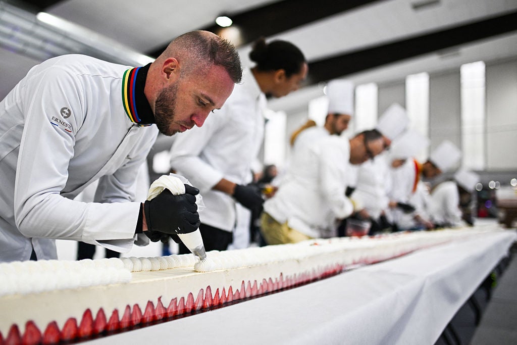 Pastry chefs work on the world's largest strawberry cake, 121,88m long during a Guinness World Record event in Argenteuil, northern suburb of Paris, on April 23, 2025. Some 350 kilos of strawberries, 150 kilos of sugar, 415 kilos of creme patissiere and 4,000 eggs: on April 23, 2025, pastry chef and owner of pastry shop La Maison Heloise, Youssef El Gatou broke the record for the world's largest strawberry cake, with a cake certified to be 121.88 metres long. (Photo by Julie SEBADELHA / AFP) (Photo by JULIE SEBADELHA/AFP via Getty Images)          