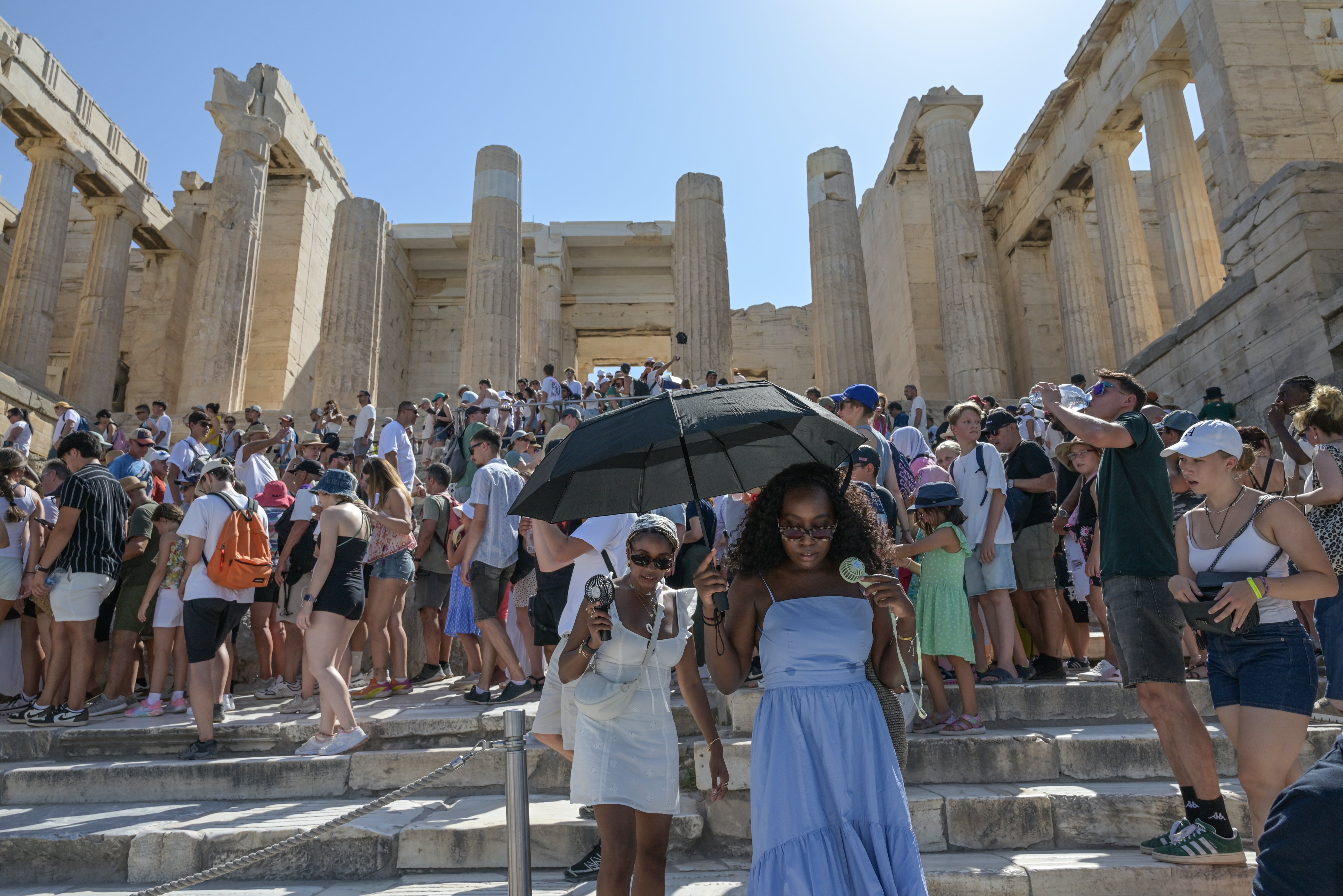 Tourists wear hats and carry umbrellas for protection as they visit the Acropolis during the worst heatwave of the season in Athens, Greece, on July 22, 2025. The Acropolis shuts between 12:00 and 17:00 to protect visitors and workers from the intense heat. (Photo by Nicolas Koutsokostas/NurPhoto via Getty Images)