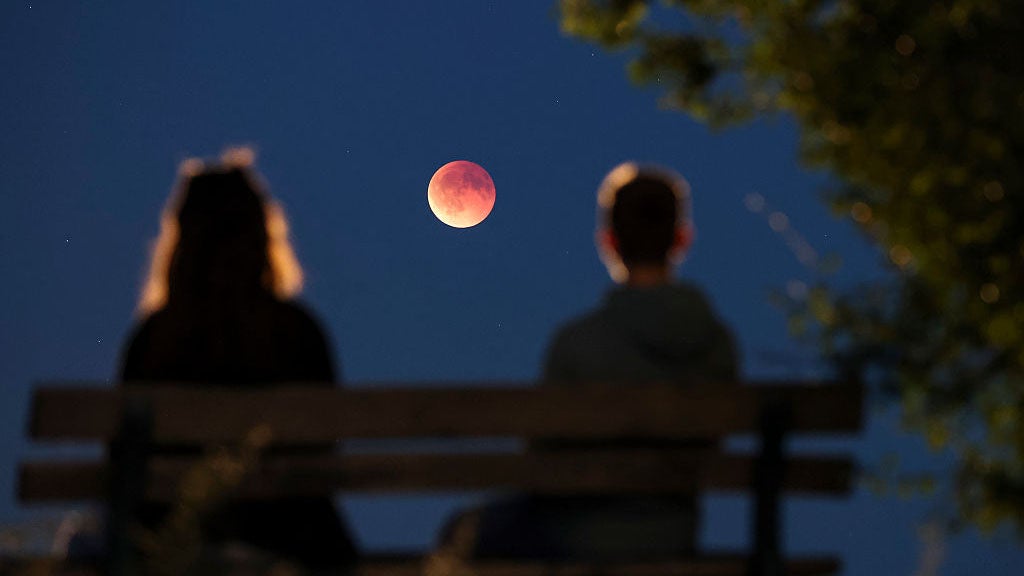 dpatop - 07 September 2025, Saxony, Leipzig: Onlookers watch the total lunar eclipse, also known as the blood moon, from a park bench. The moon gradually moves into the Earth's shadow - until it becomes a total lunar eclipse. Photo: Jan Woitas/dpa (Photo by Jan Woitas/picture alliance via Getty Images)