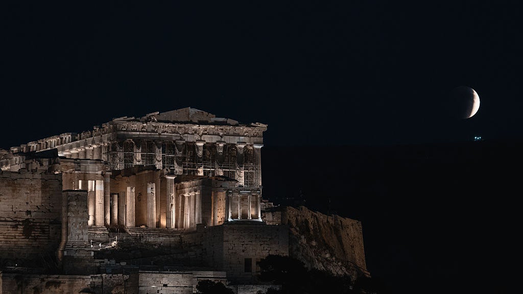 A total lunar eclipse, known as a ''blood moon,'' rises beside the illuminated Parthenon temple at the Acropolis in Athens, Greece, on September 7, 2025. (Photo by Daniel Yovkov/NurPhoto via Getty Images)