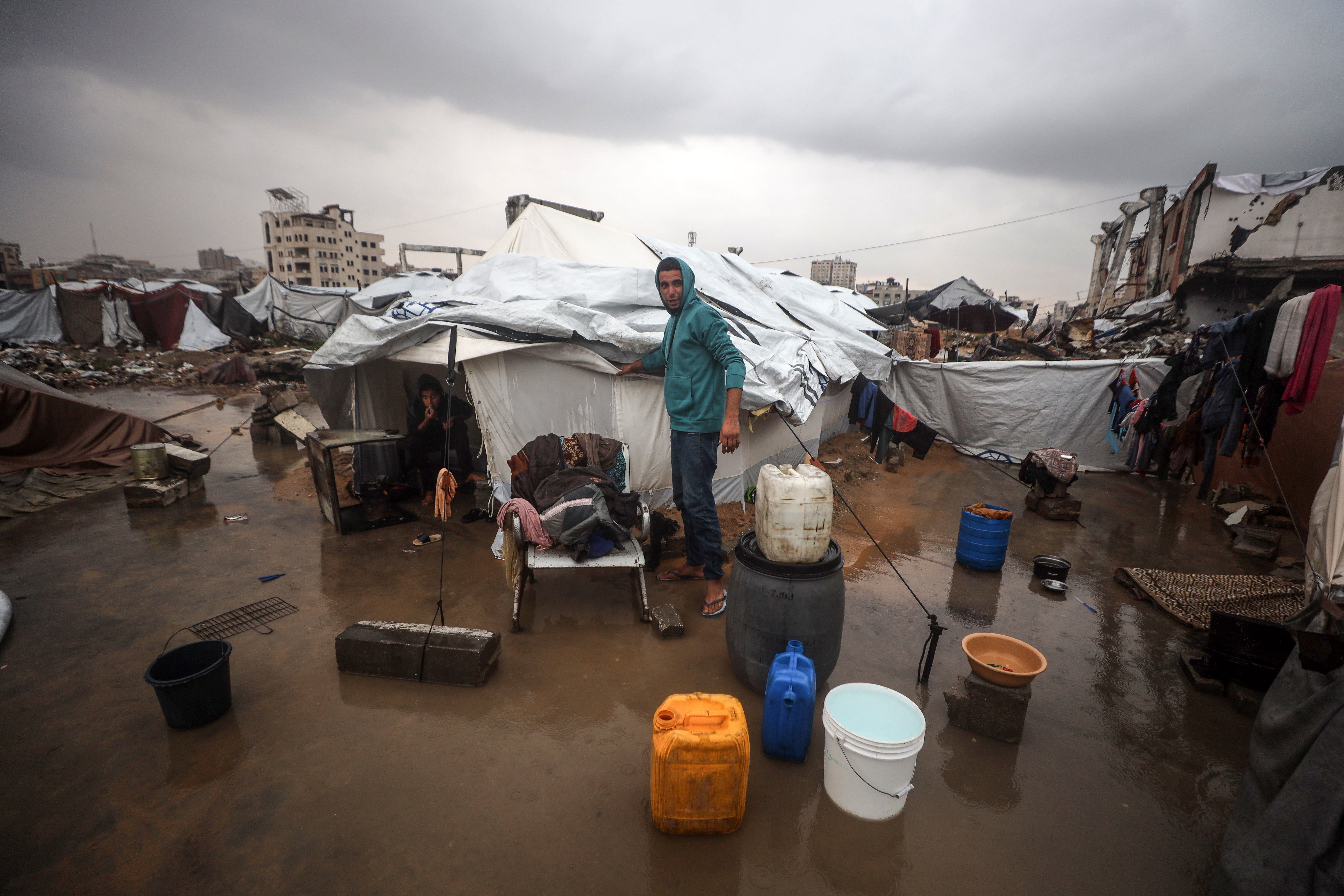 Palestinians walk outside their tent at a makeshift camp sheltering displaced Palestinians after heavy rains in Gaza City, Palestine, on December 12, 2025. (Photo by Majdi Fathi/NurPhoto via Getty Images)