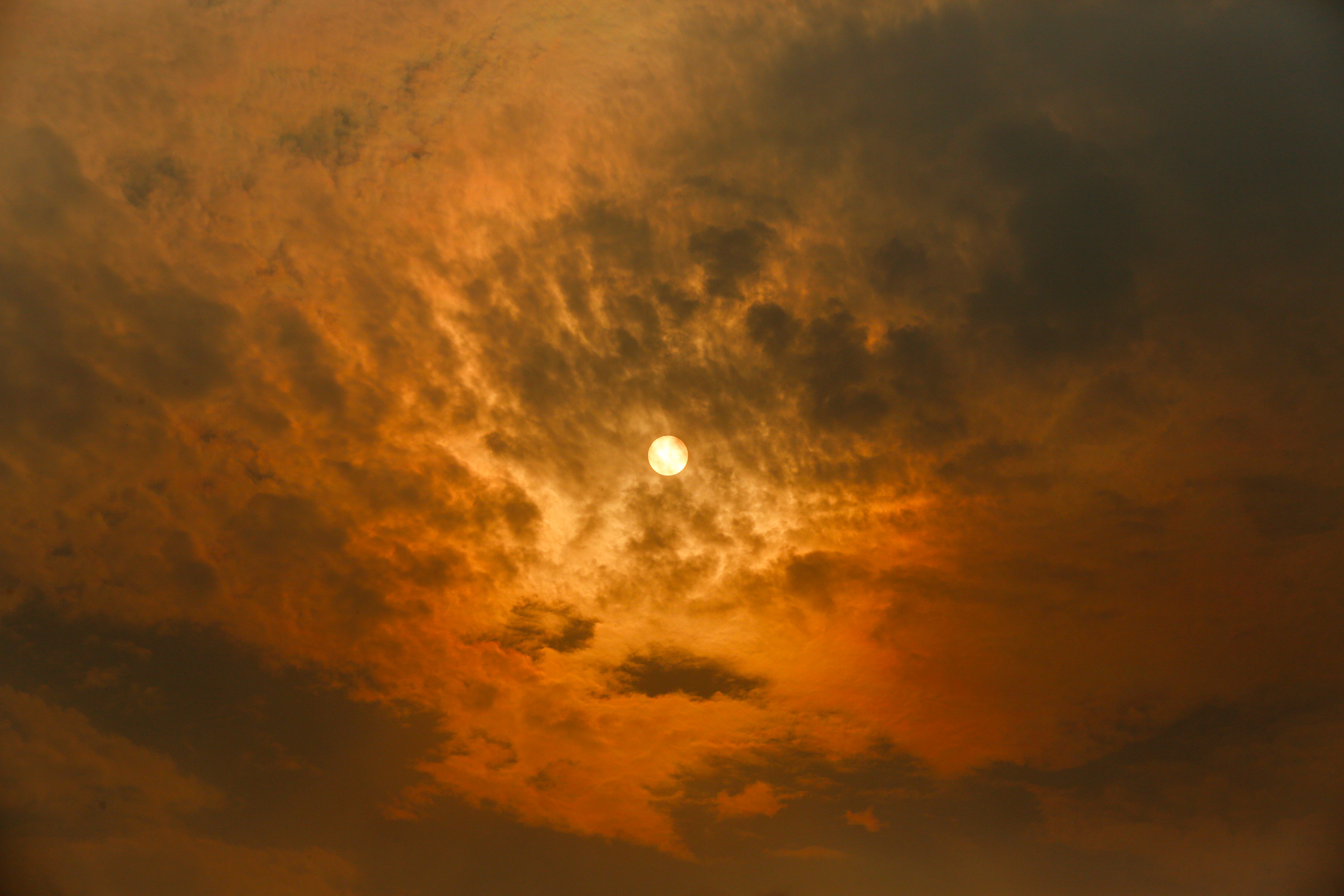 MELBOURNE, VICTORIA, AUSTRALIA - 2026/01/09: The sun casts an orange hue across the sky as smoke from bushfires drifts over Docklands. Smoke from multiple bushfires and grassfires burning the city is affecting air quality and visibility, turning the sky red. The Department of Environment, Land, Water and Planning (DELWP) has issued a community information message advising that smoke and ash may be seen or smelled in areas far from the fires. Residents are urged to take precautions especially those with respiratory conditions as bushfire activity continues. (Photo by Ye Myo Khant/SOPA Images/LightRocket via Getty Images)