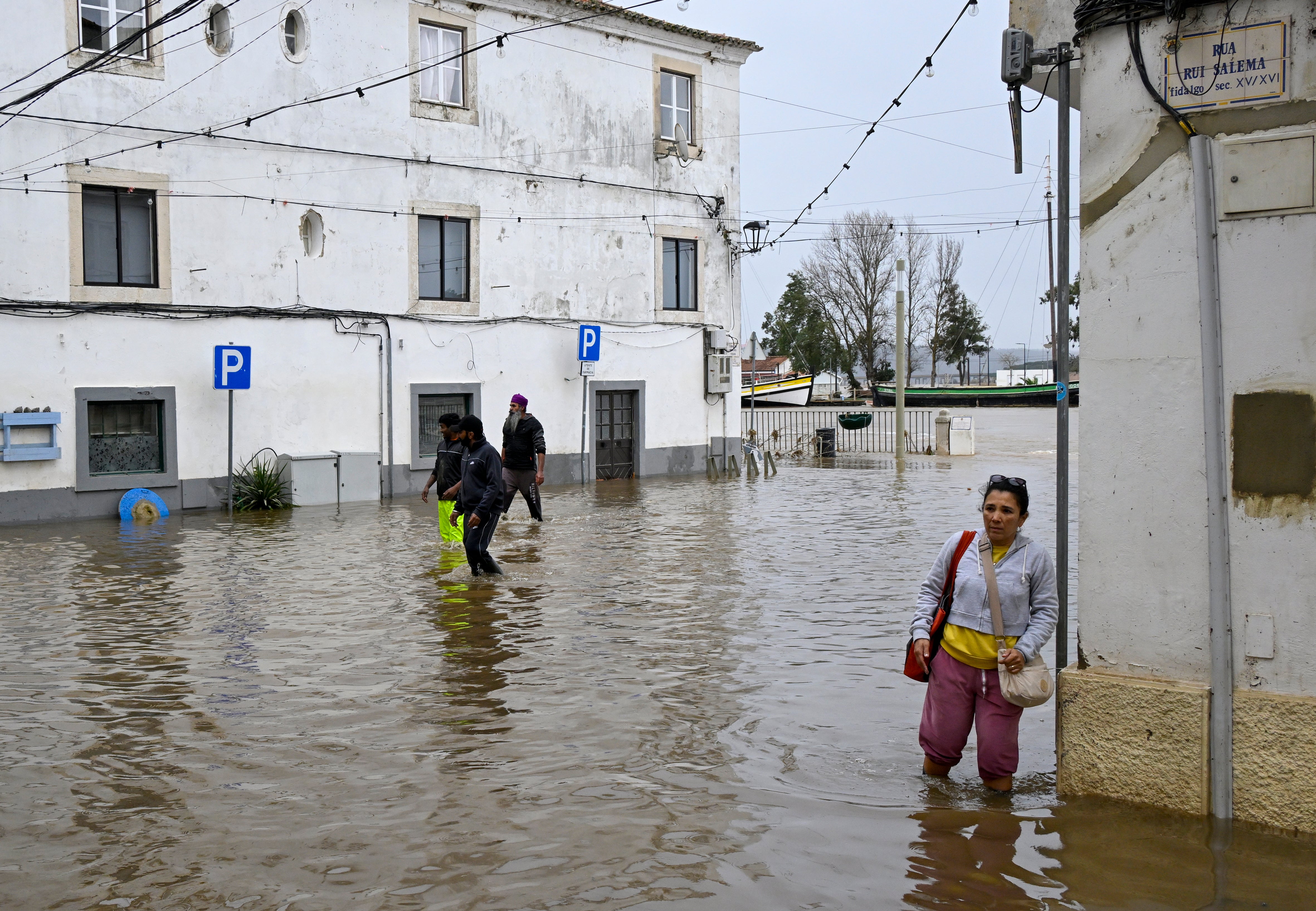 ALCACER DO SAL, PORTUGAL - FEBRUARY 06: A woman wades through a flooded street as neighbors and helpers salvage furniture and other elements from homes and stores affected in the riverside area that was completely flooded due to depression "Leonardo" hitting the country in the aftermath of depression "Kristin" on February 06, 2026 in Alcacer do Sal, Portugal. Days after storms Ingrid, Joseph and Kristin, the latter being the most severe hitting Portugal, storm Leonardo has arrived and is already causing damage. The bad weather has caused so far 12 fatalities, and the government has extended the state of calamity until February 15. (Photo by Horacio Villalobos#Corbis/Getty Images)