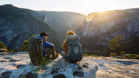 A couple sitting on a ledge while backpacking in Yosemite Valley.