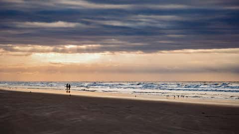 A couple beneath beautiful sun rays above the Atlantic Ocean in Kiawah Island, South Carolina.