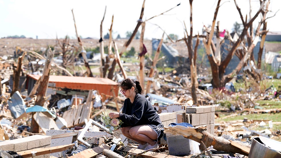 Kimberly Ergish holds flowers as she cleans out belongs from her tornado damaged home, Wednesday, May 22, 2024, in Greenfield, Iowa. (AP Photo/Charlie Neibergall)